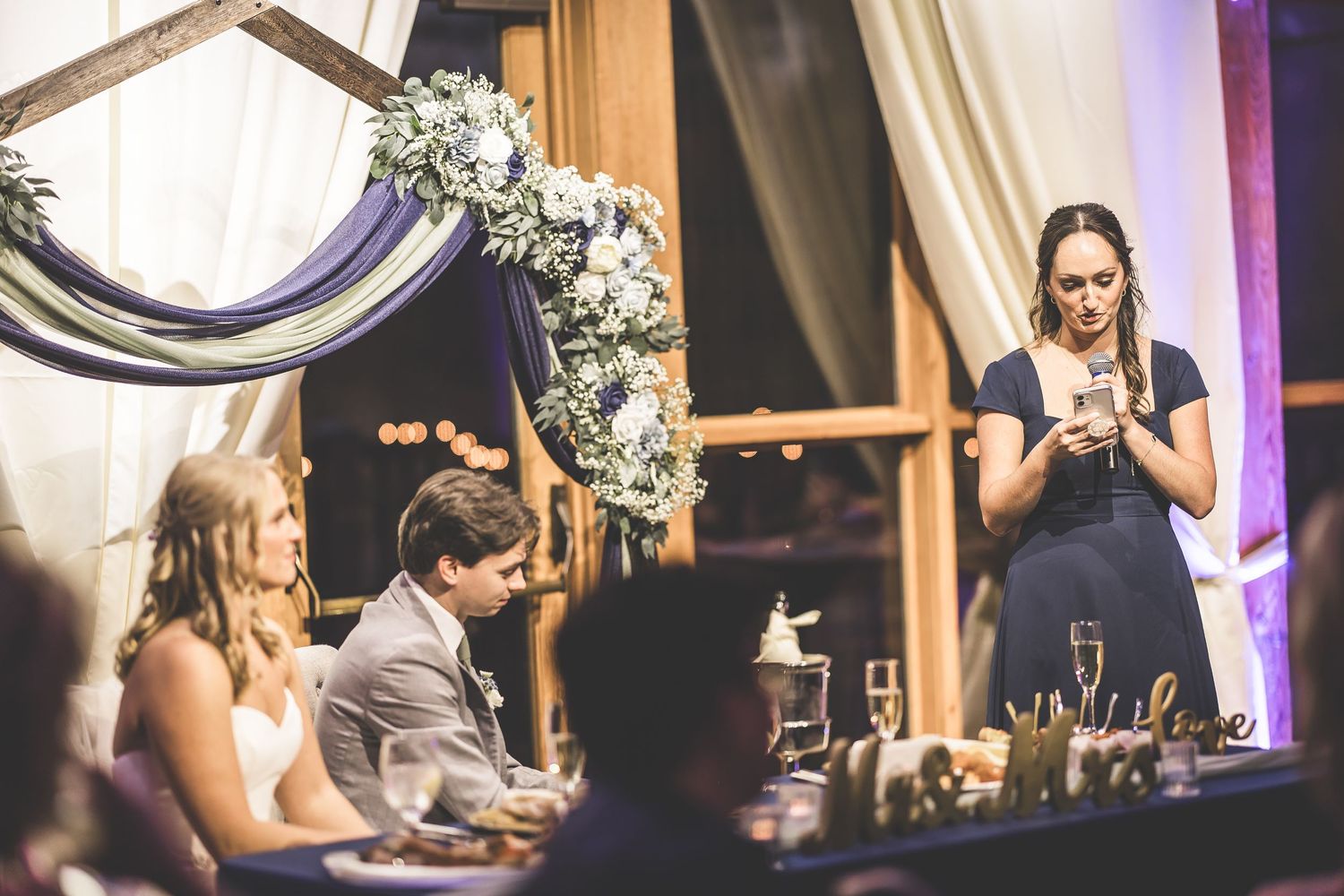 Couple sharing a romantic moment at their rustic barn wedding reception with elegant white draping and floral decor.