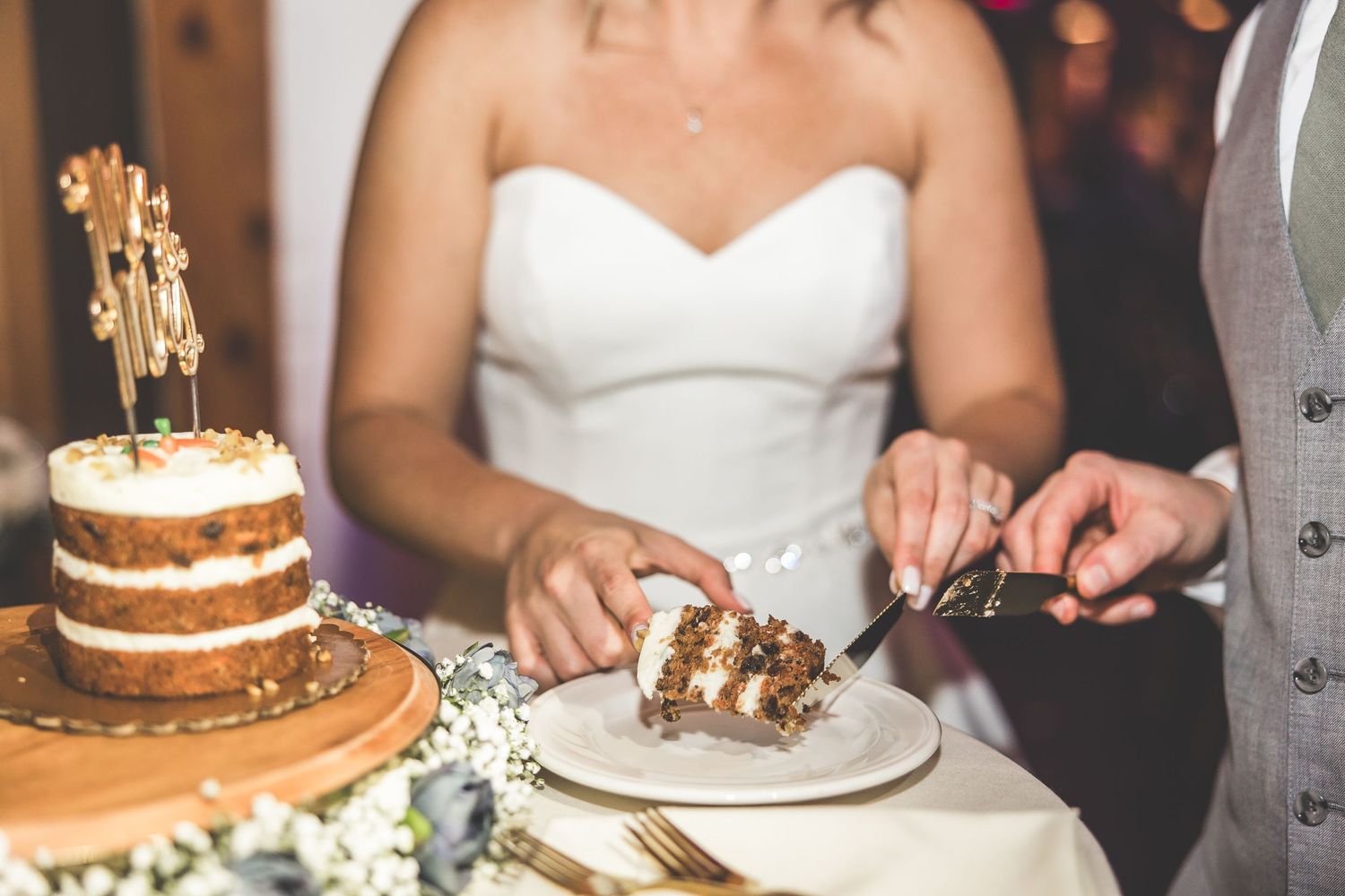 Close-up of a rustic three-tiered naked wedding cake being cut during reception.
