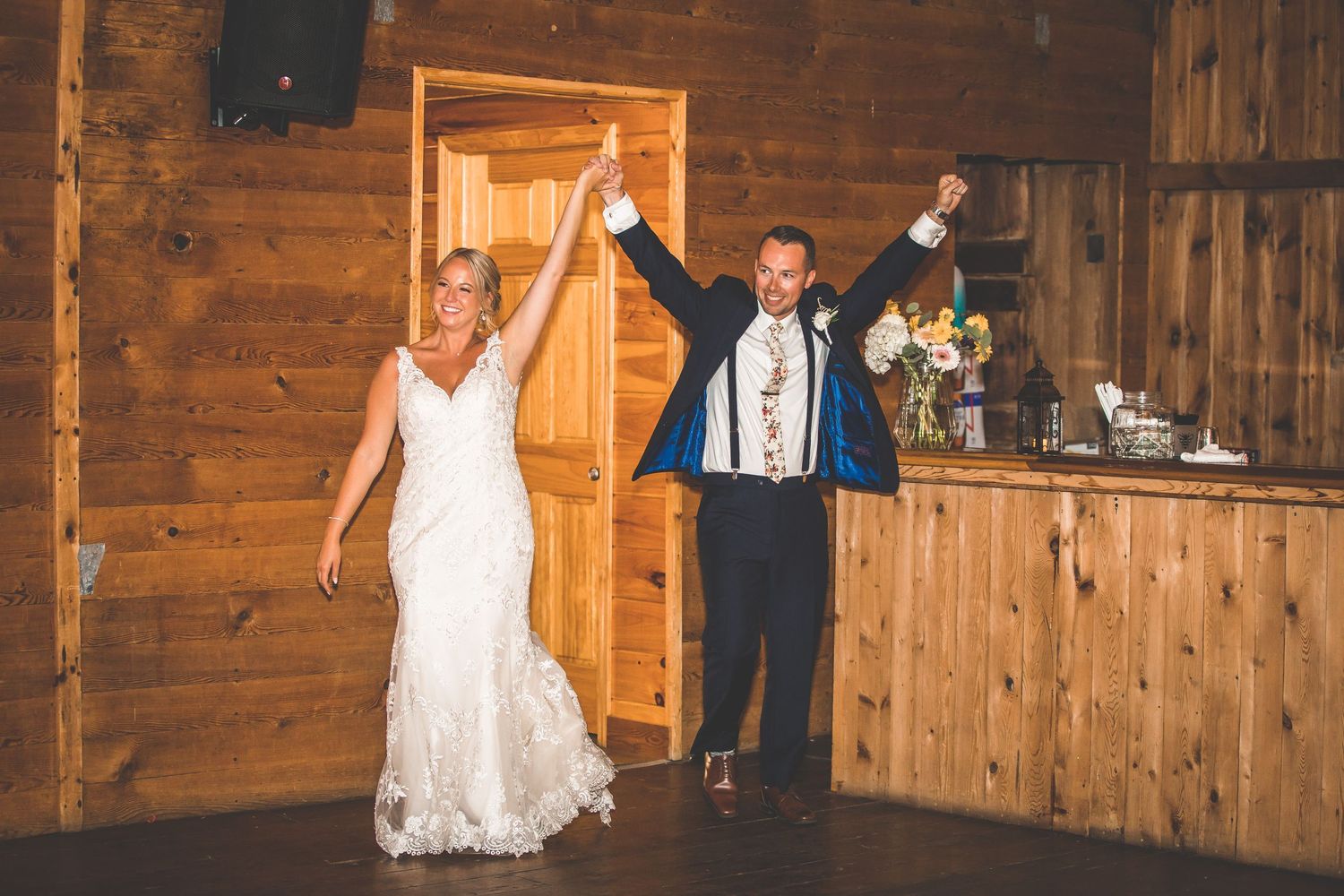 Wedding celebration with dancing and entertainment inside wooden barn venue.
