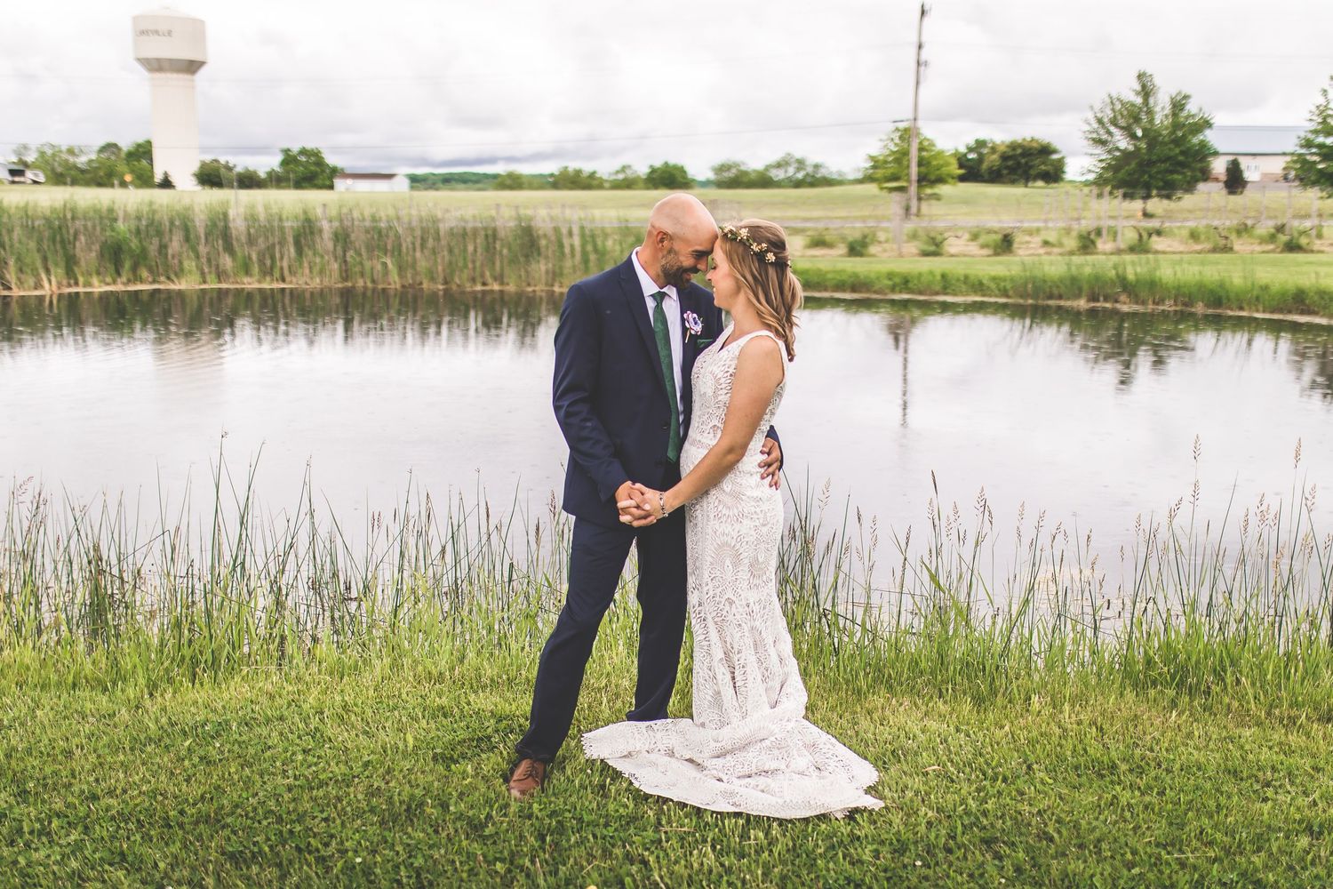 A serene lakeside wedding portrait with tall grasses and calm waters.