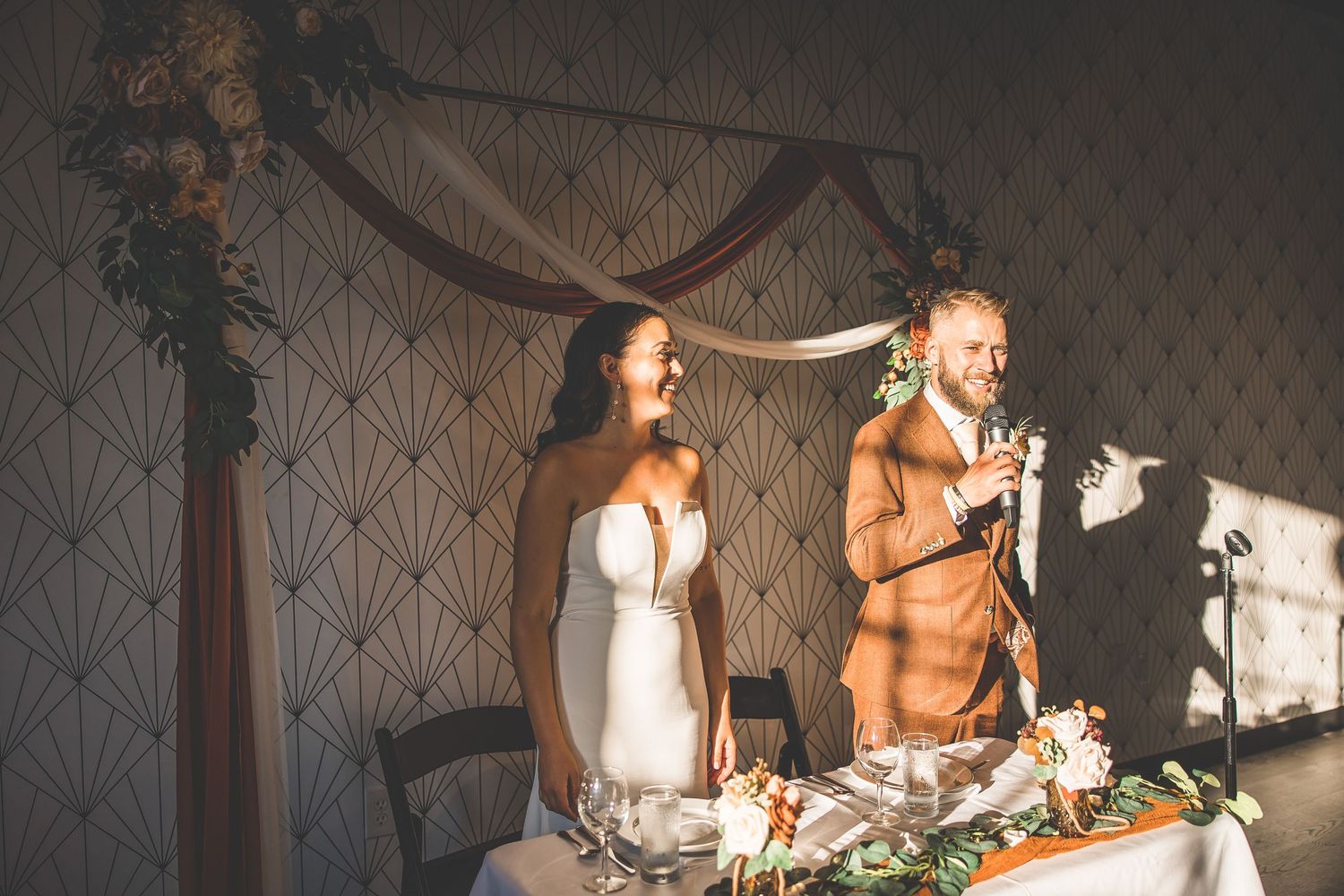 Wedding reception moment captured during speeches at a decorated head table.