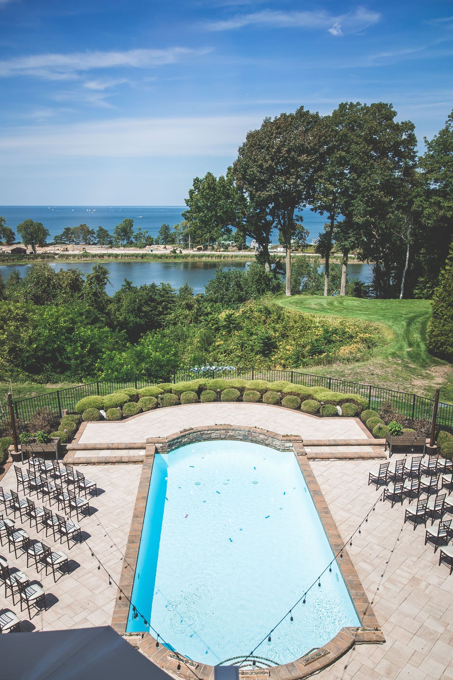 Outdoor wedding venue with swimming pool and rows of chairs overlooking the ocean.