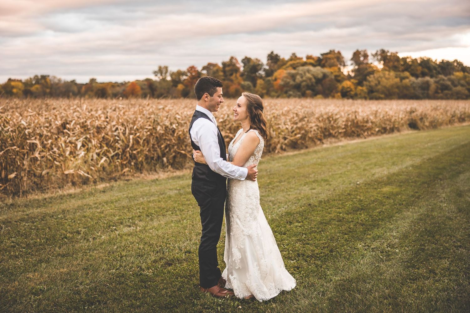 Couple poses in golden field during sunset wedding photo session.