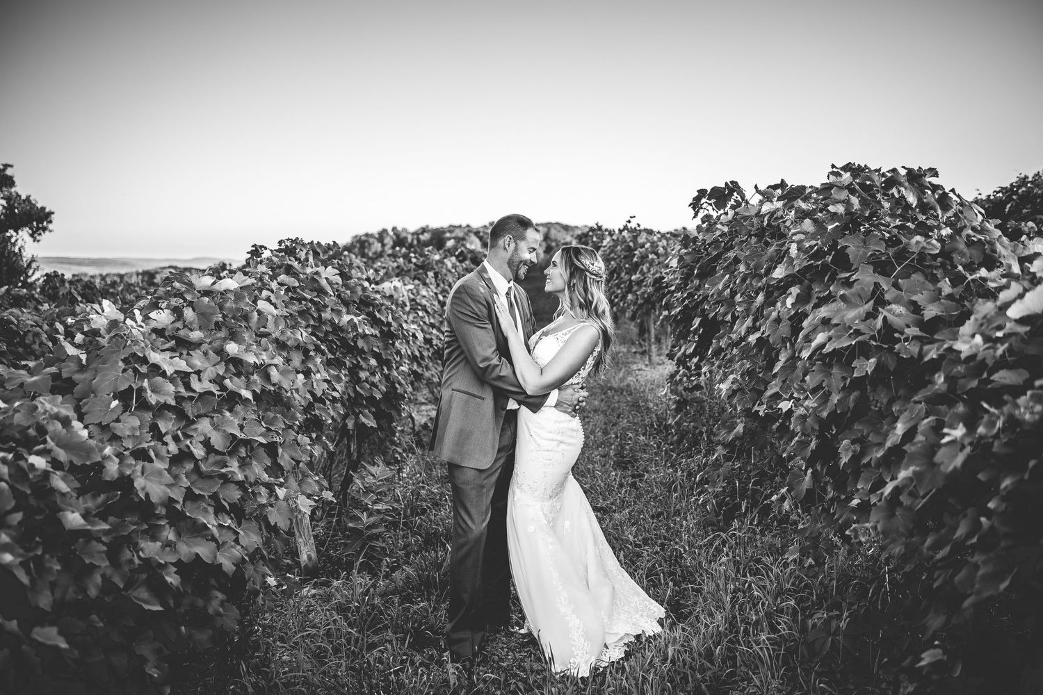 Black and white panoramic of couple among tall grasses in natural outdoor setting.