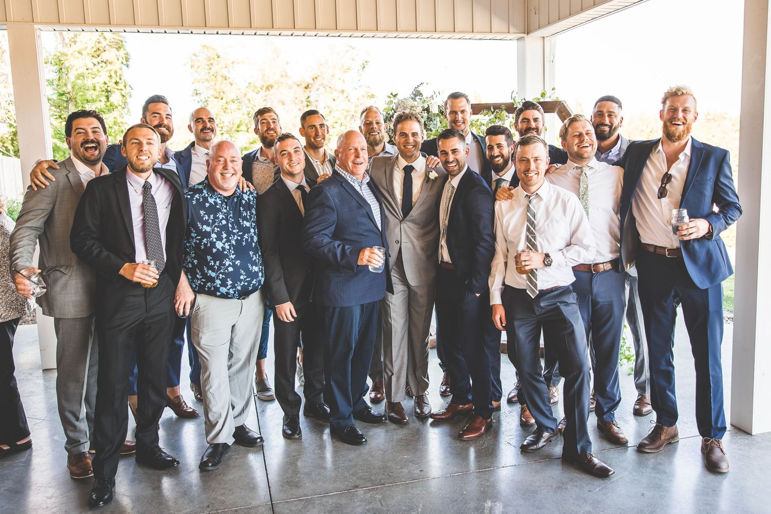 Panoramic group photo of wedding guests lined up outside a covered venue.