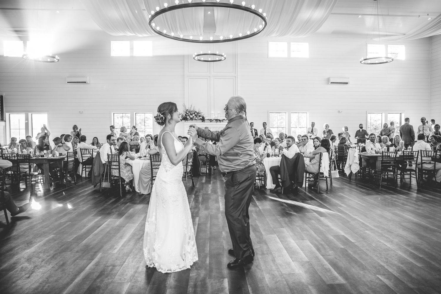 A black and white photo captures an intimate dance moment at a wedding reception.