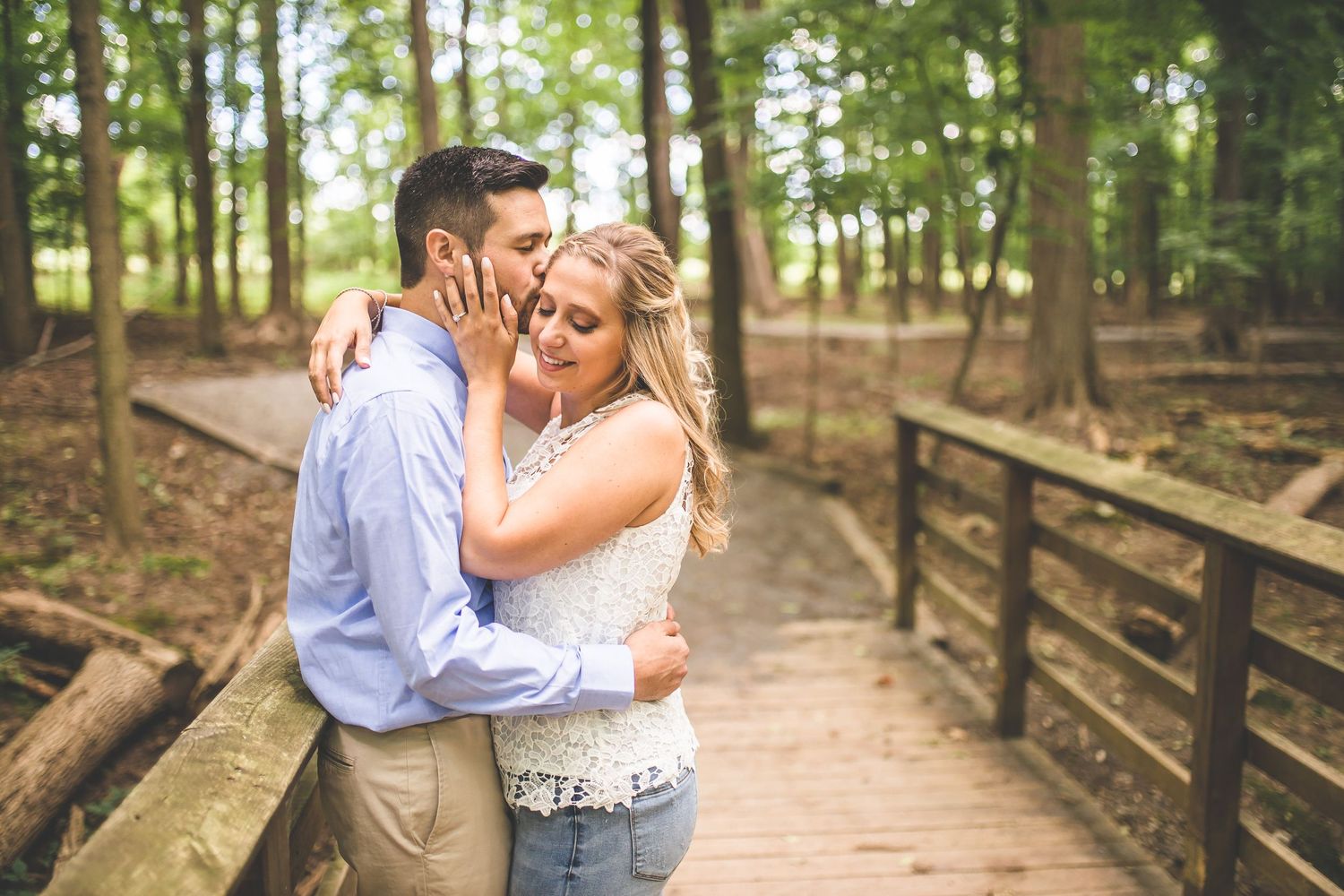 Romantic couple photos on a wooden boardwalk surrounded by lush forest.