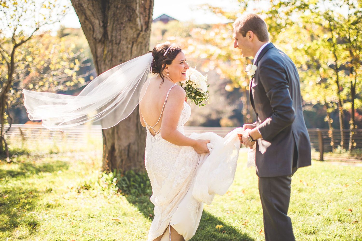 Autumn wedding photoshoot with golden sunlight streaming through trees in park setting.