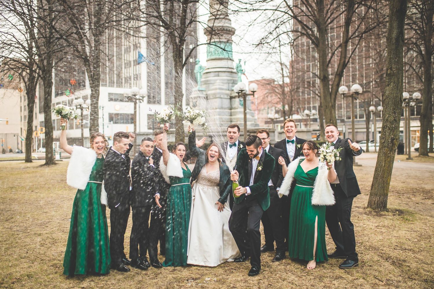 Wedding party in formal attire poses outdoors in winter with emerald green accents.