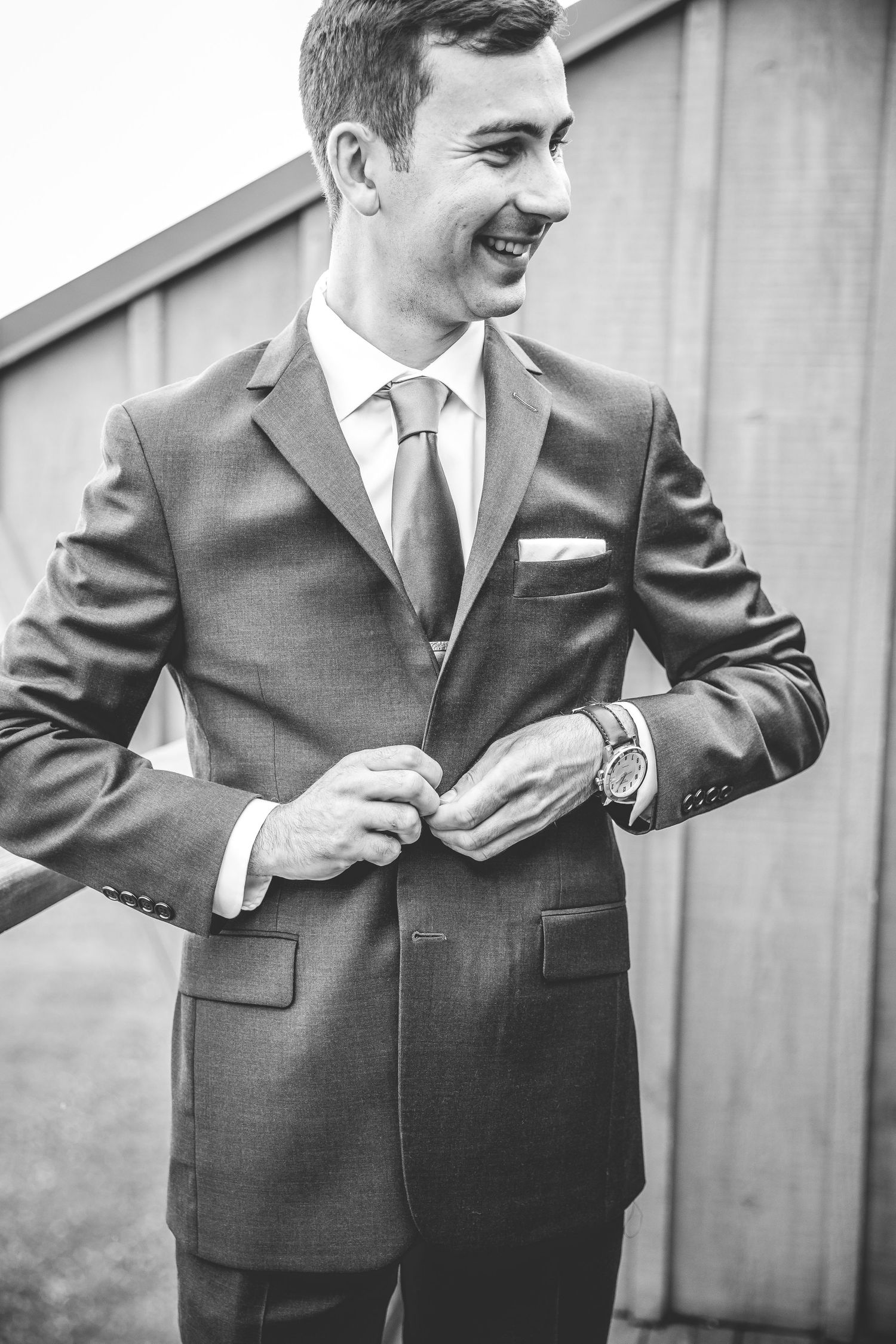Close-up shots of a groom adjusting his suit jacket and tie before the wedding ceremony.