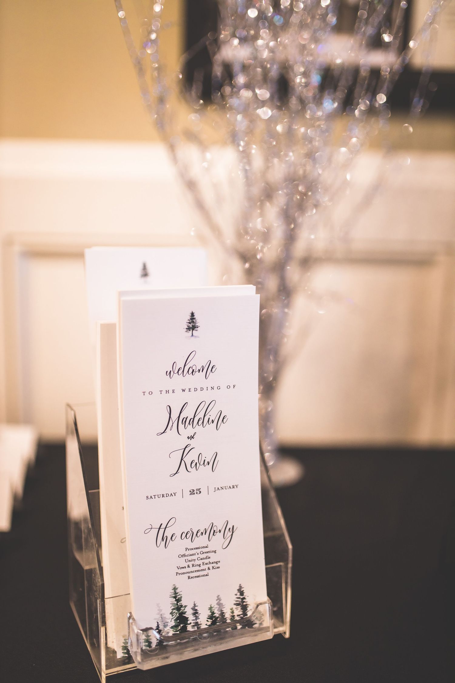 Winter-themed wedding reception table cards with pine tree motifs and elegant calligraphy.