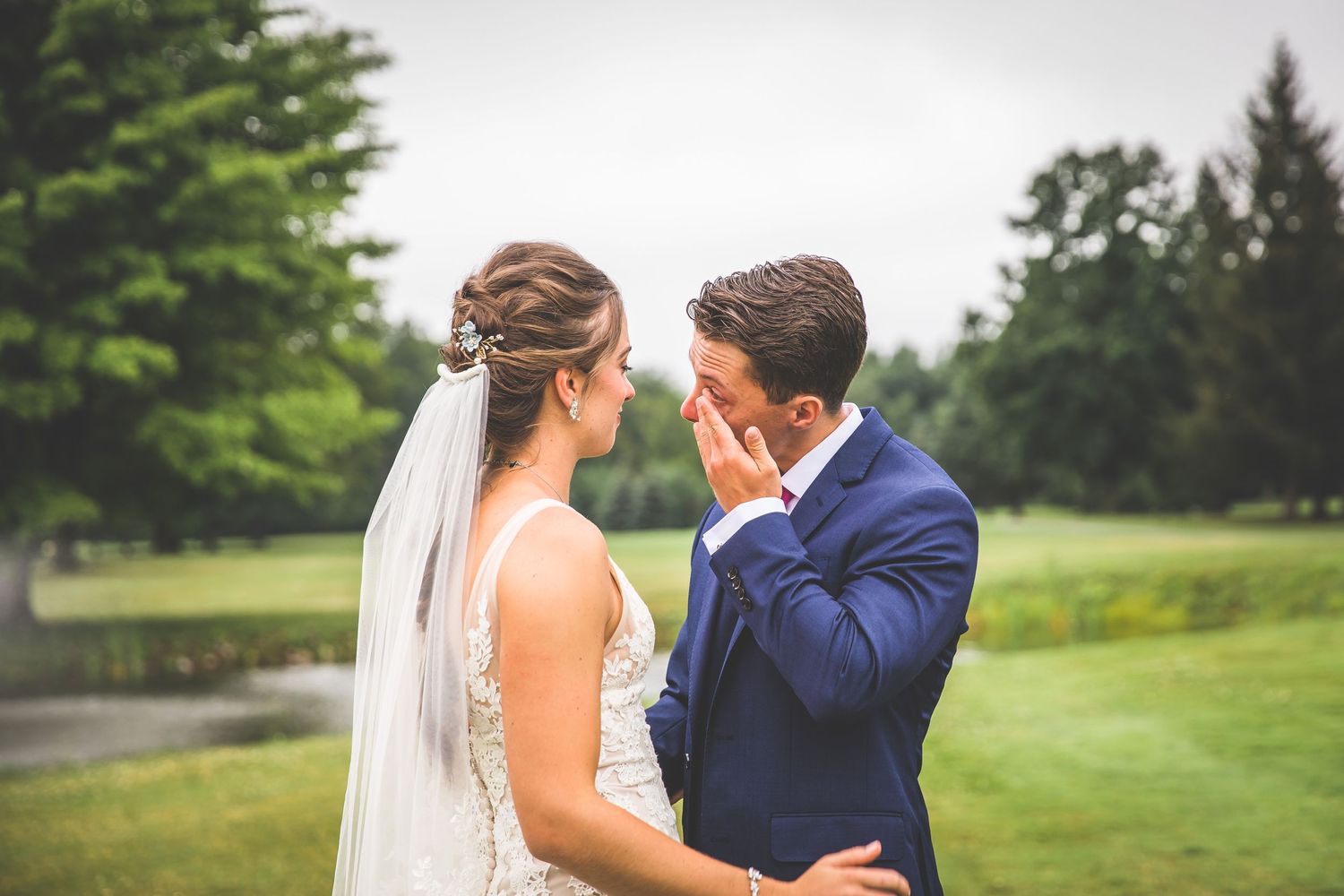 An intimate wedding moment shared between a couple on manicured grounds with a water feature.