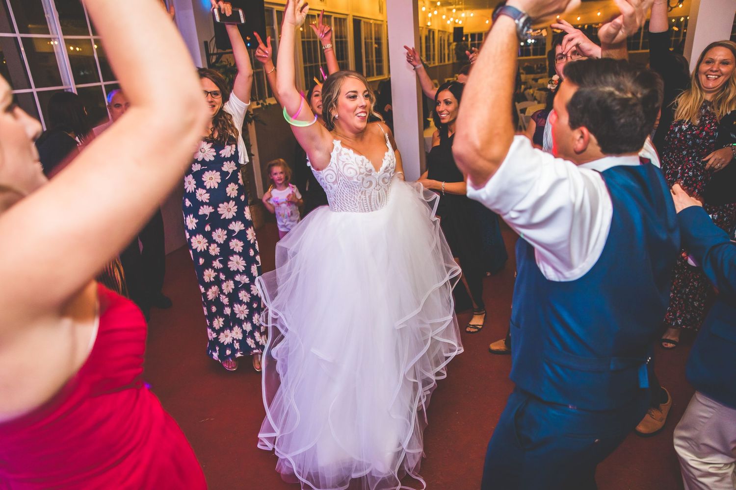 A joyful celebration on the dance floor with a bride in a white tulle dress dancing among wedding guests.