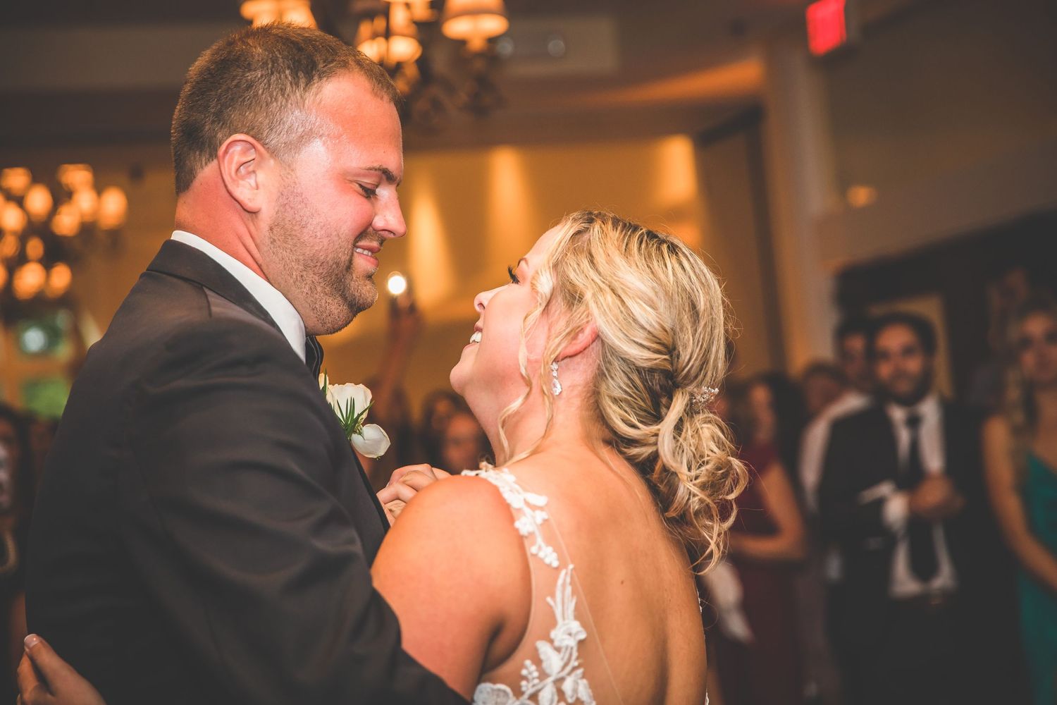 Newlyweds share a joyful laugh while dancing together at their reception.