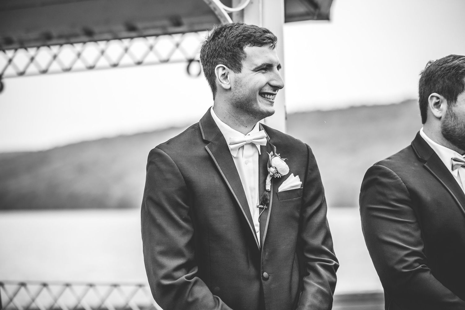 Groomsmen in black tuxedos stand in line during wedding ceremony.