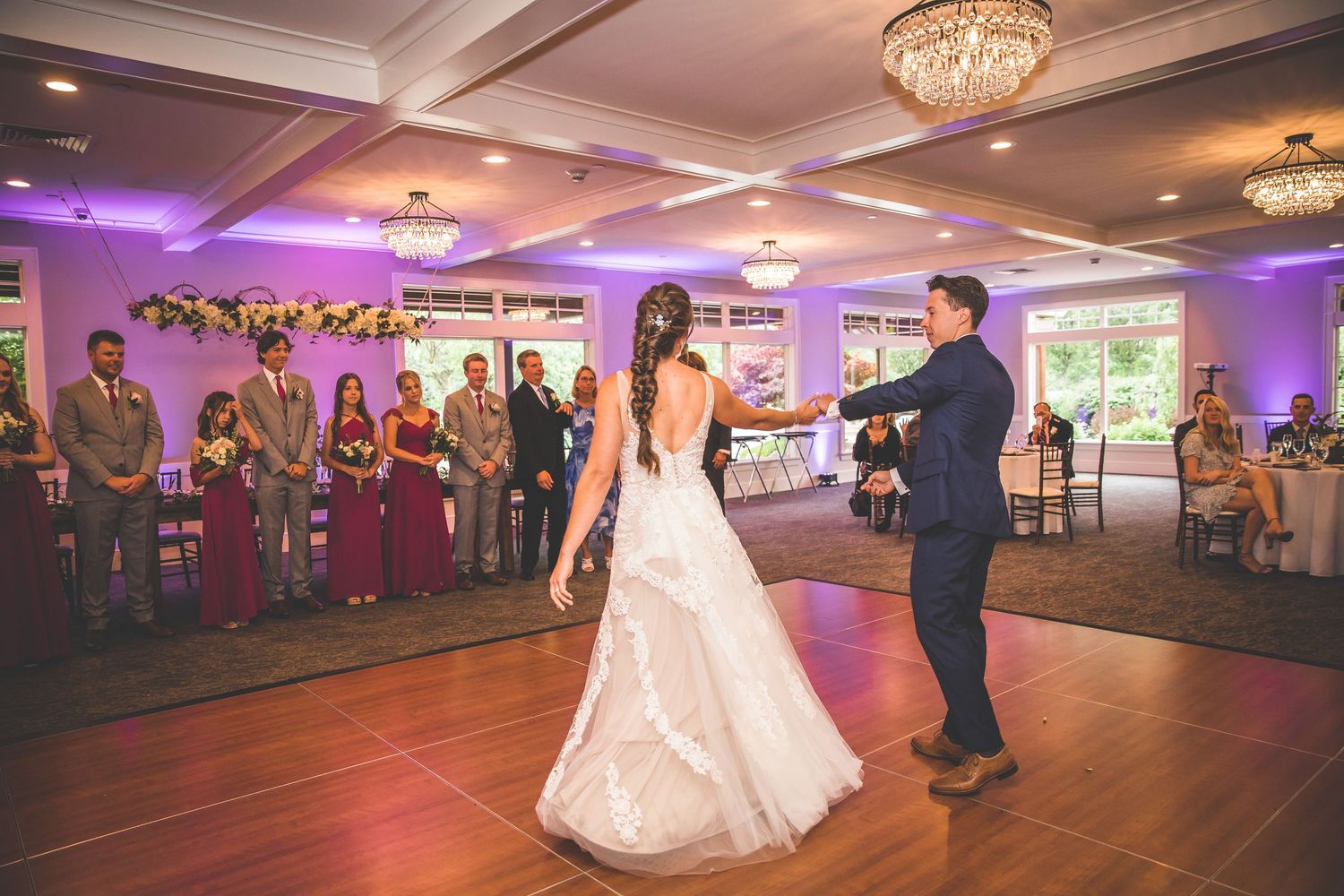 Wedding reception panorama showing couple dancing in an elegant ballroom with purple accent lighting.
