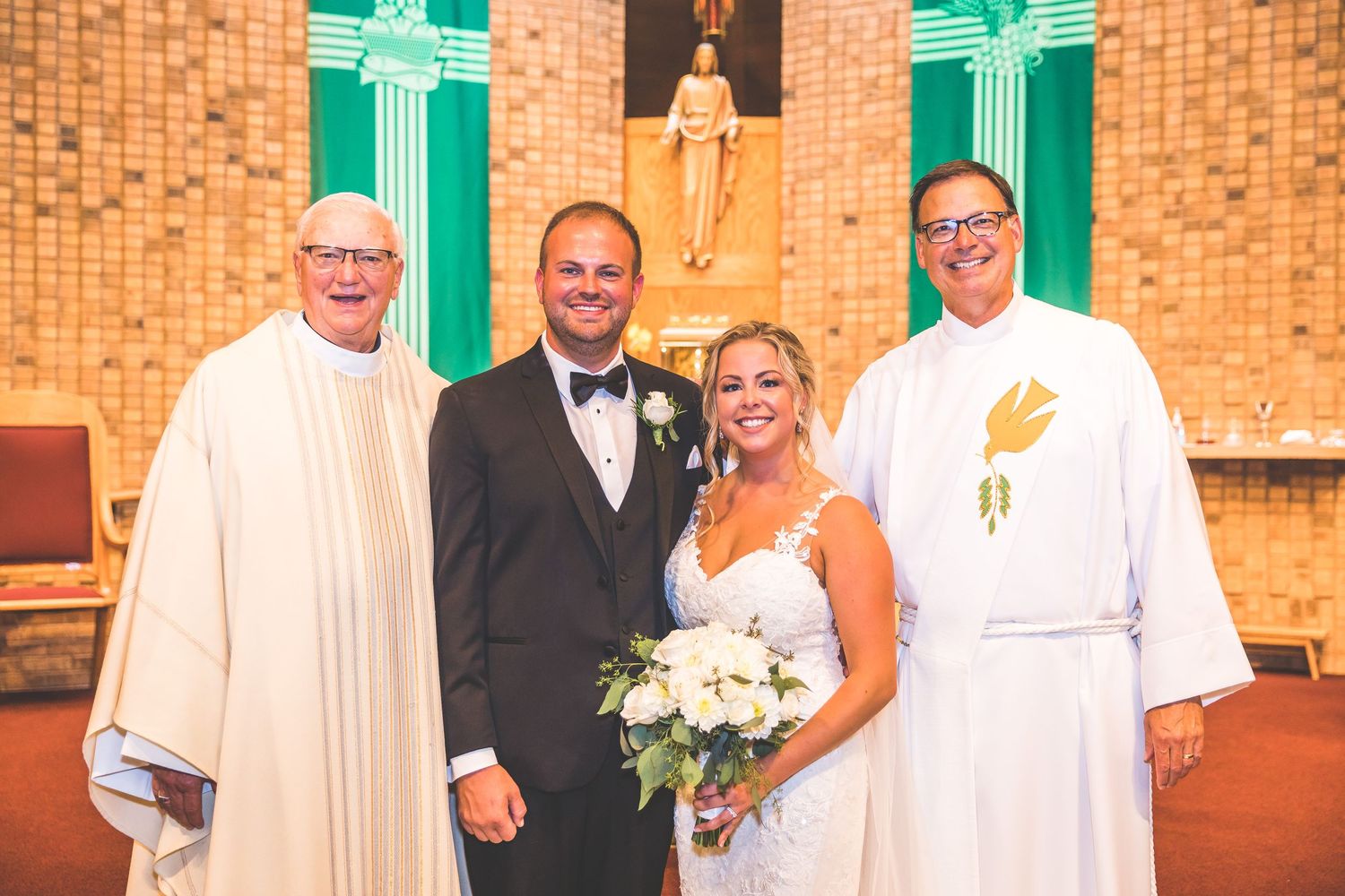 Wedding party poses in front of green church doors and brick walls.