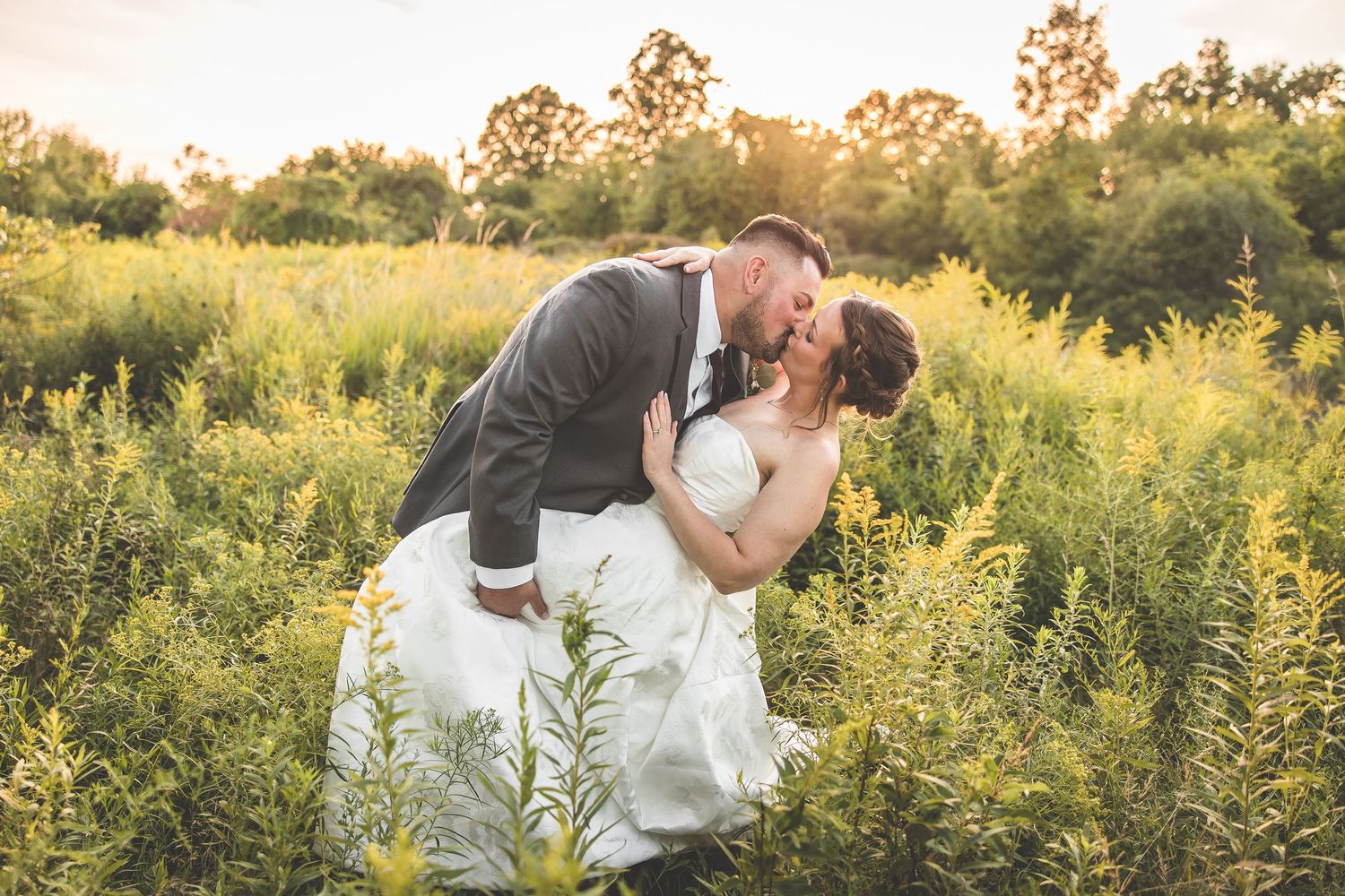 Sunset wedding portraits in a golden field during magic hour.