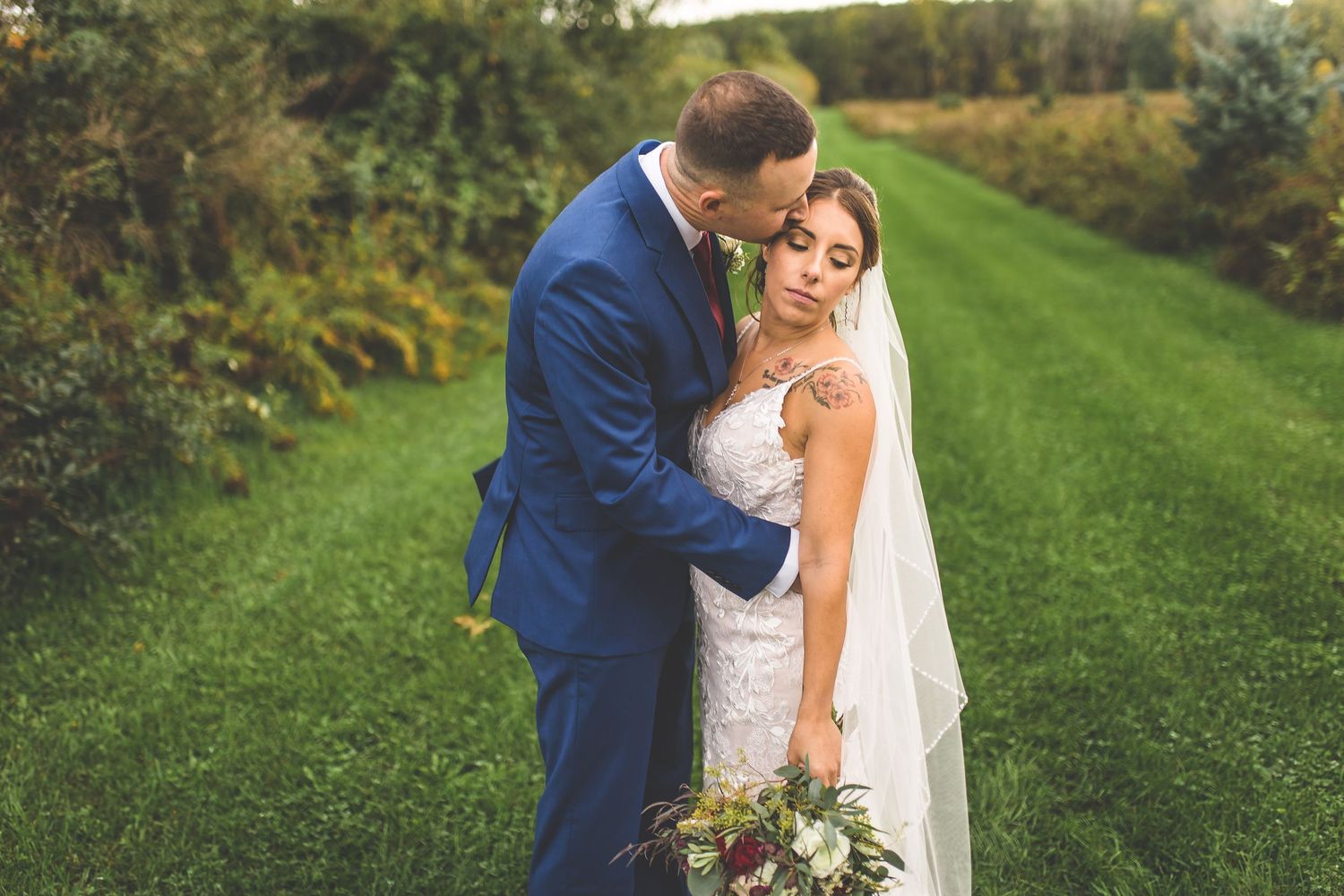 Romantic wedding portraits taken in a verdant outdoor setting with natural lighting.