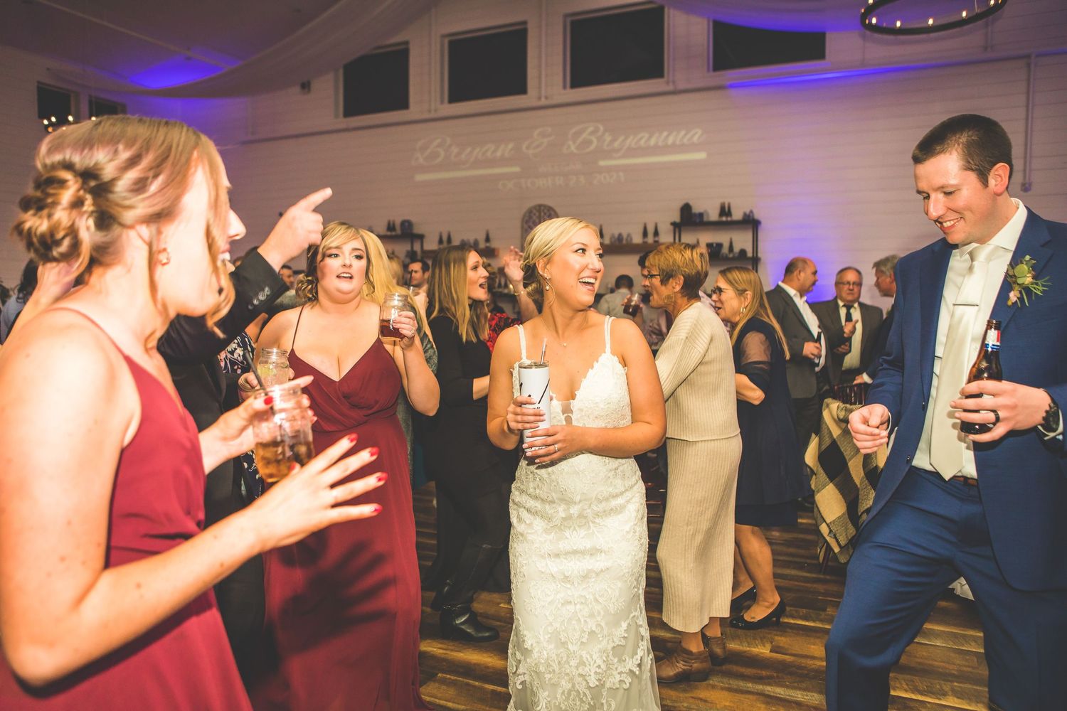 Wedding reception guests dancing and celebrating on a lively dance floor with blue uplighting.