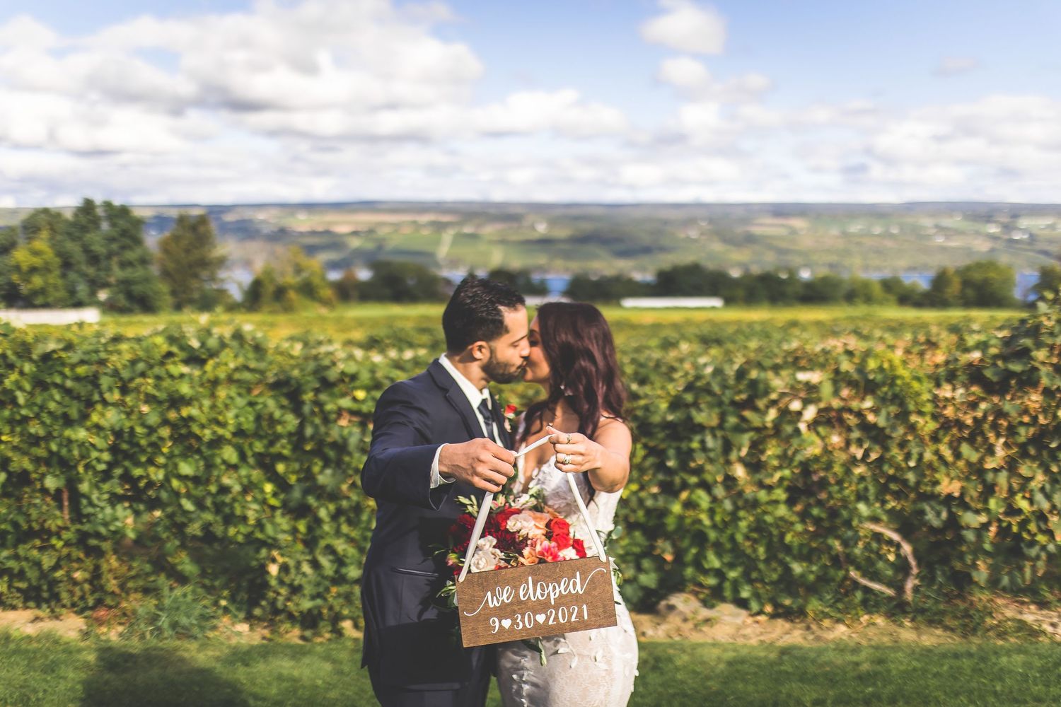 Couple celebrating with champagne in a scenic vineyard setting.