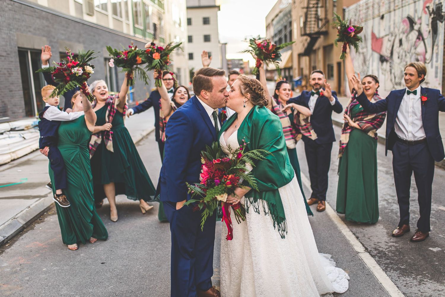 Wedding celebration group shot with bridal party in emerald green and navy blue attire.