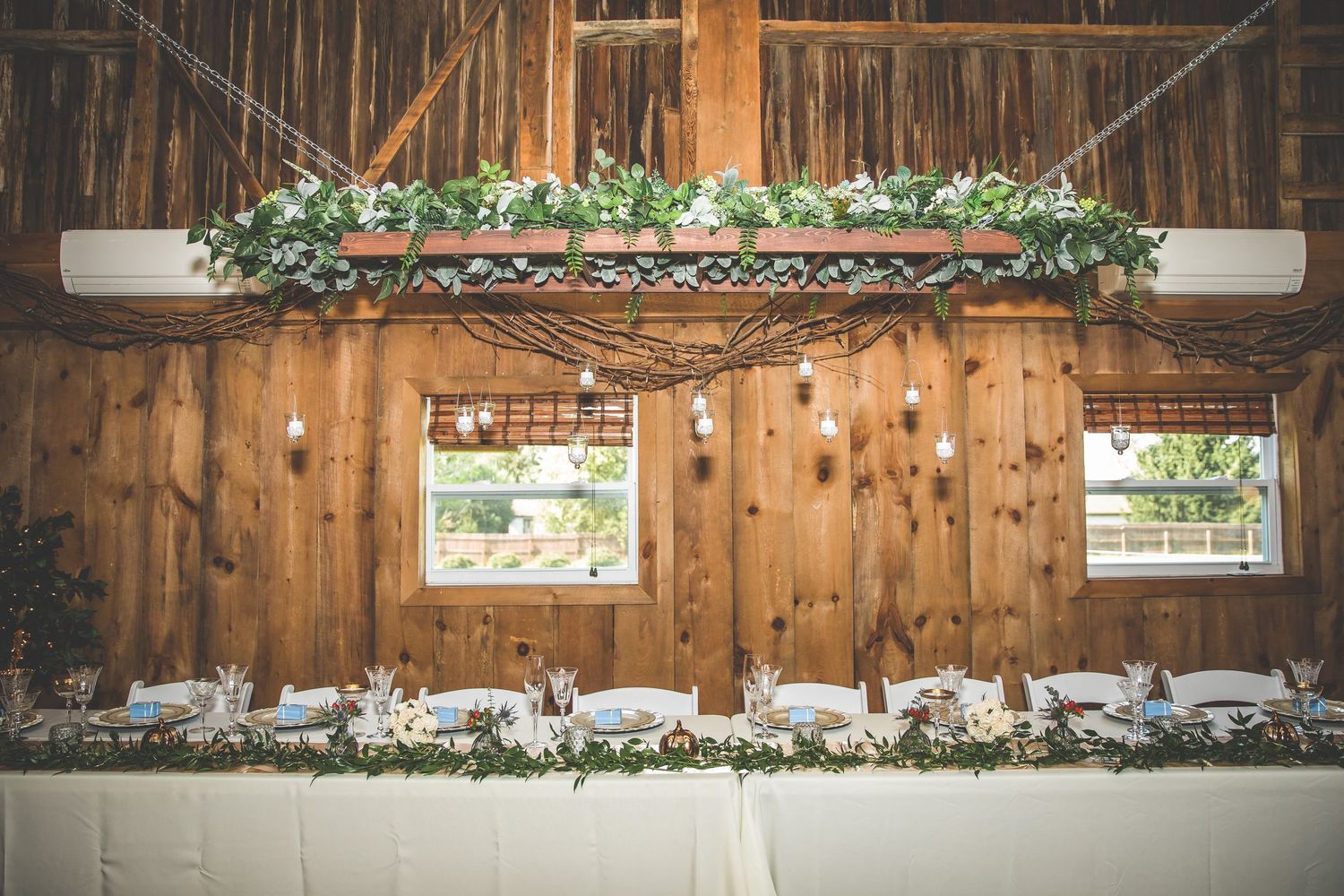 Rustic barn wedding venue interior with wooden beams and string lights creating a warm ambiance.