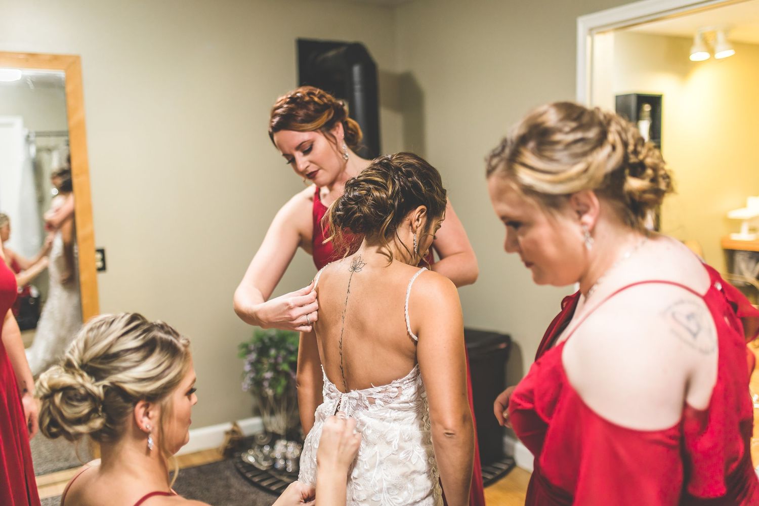 Wedding party preparations with bridesmaids in red dresses helping with final touches.