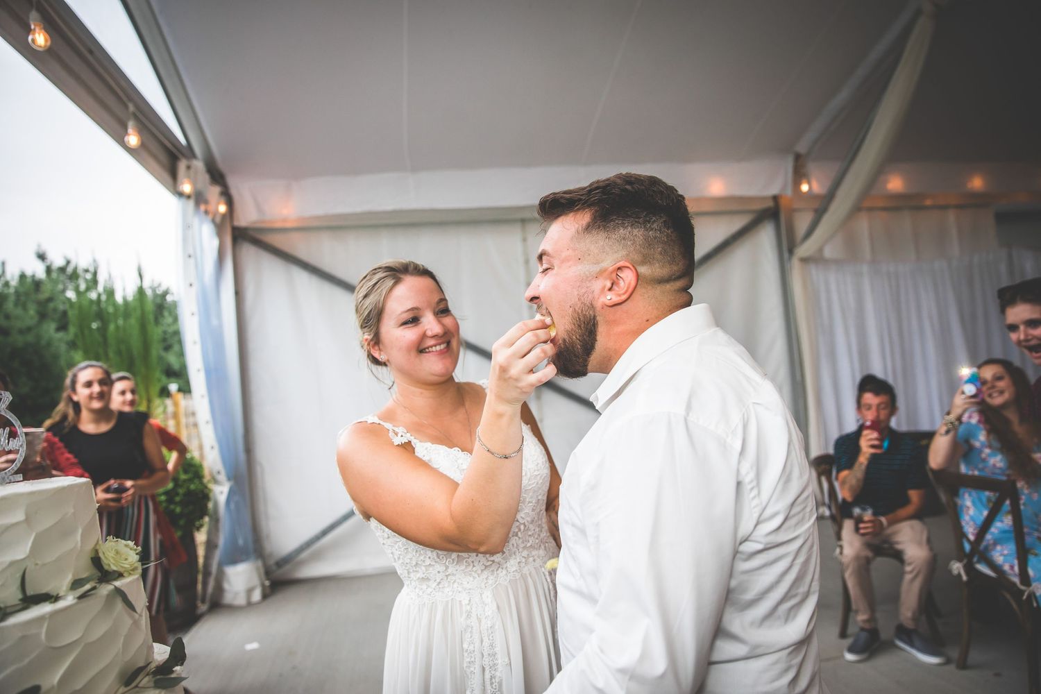 Couple dancing together at a wedding reception under a white tent.