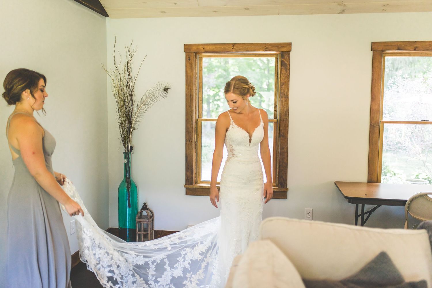 Bride getting dressed in simple white wedding gown in rustic room with wooden trim.