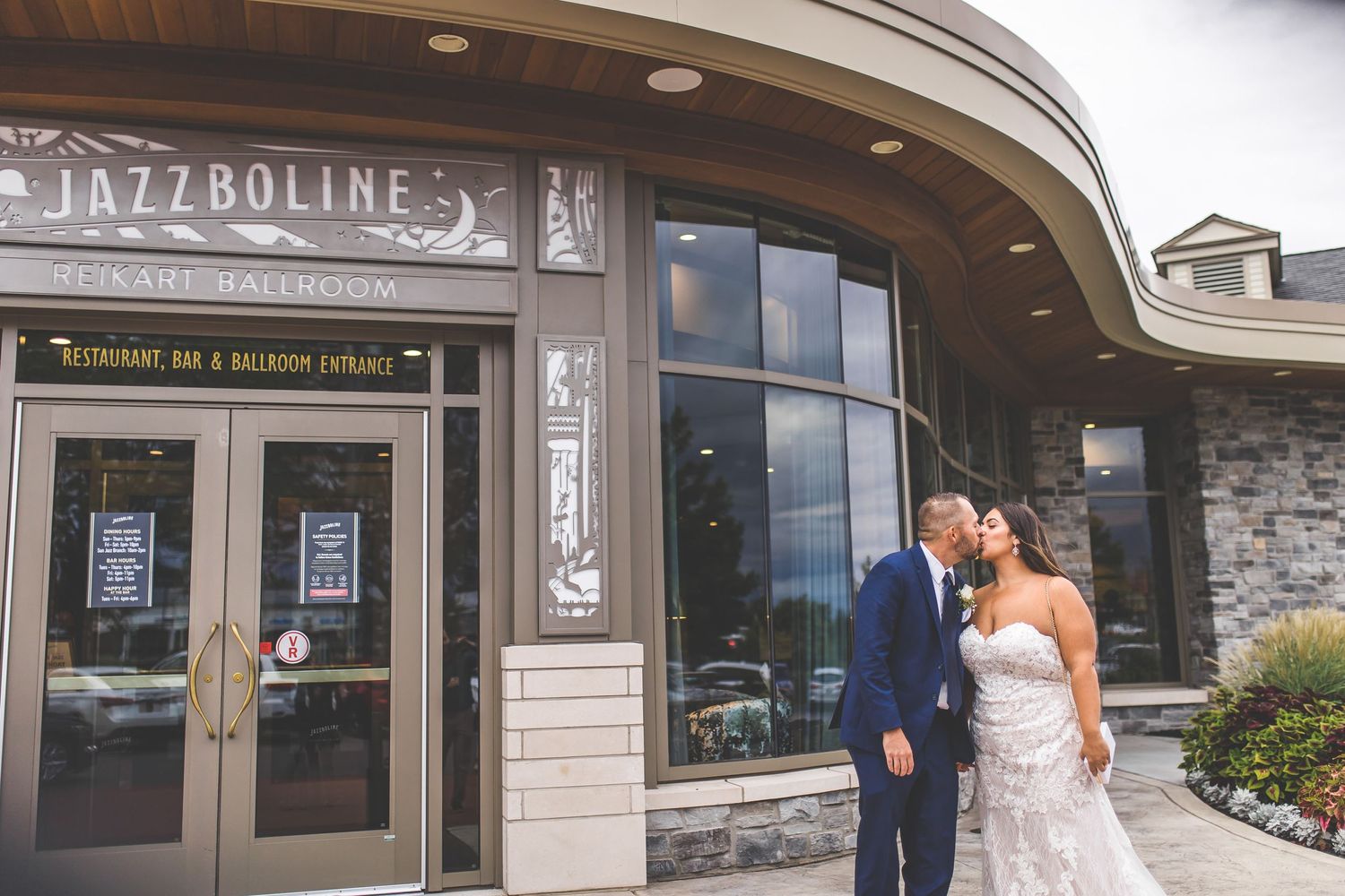 Couple poses outside Jazzboline restaurant with modern architectural details.