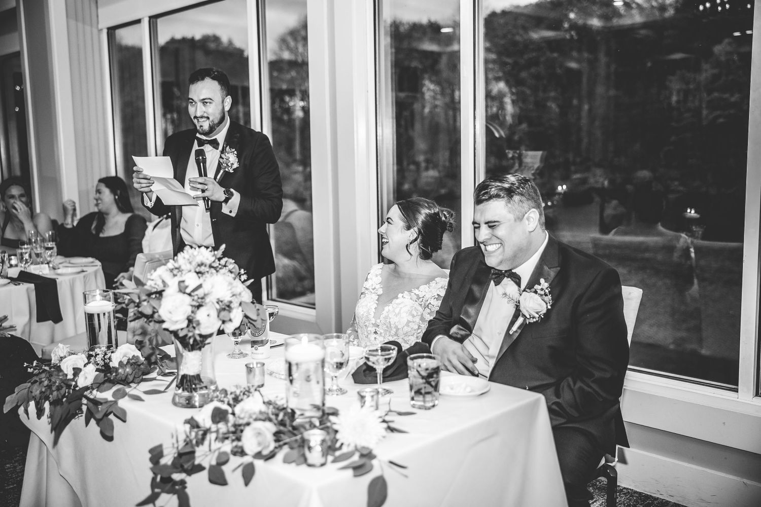 Wedding reception guests raise their glasses in a celebratory toast at an elegant indoor venue.
