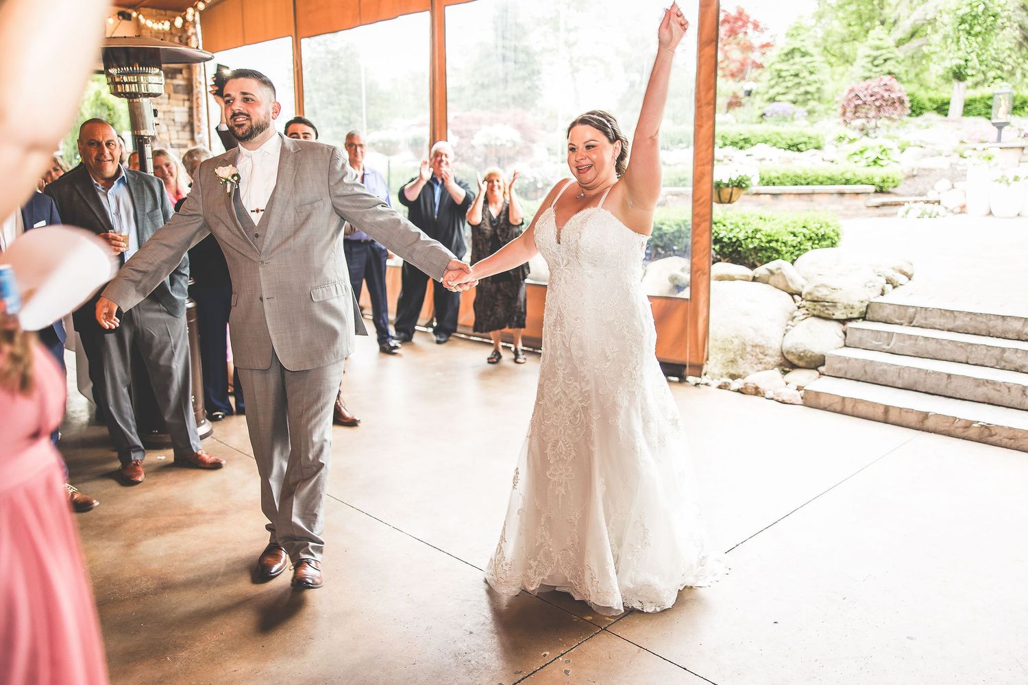 Wedding party celebrates with joyful dancing in an outdoor venue decorated with string lights.