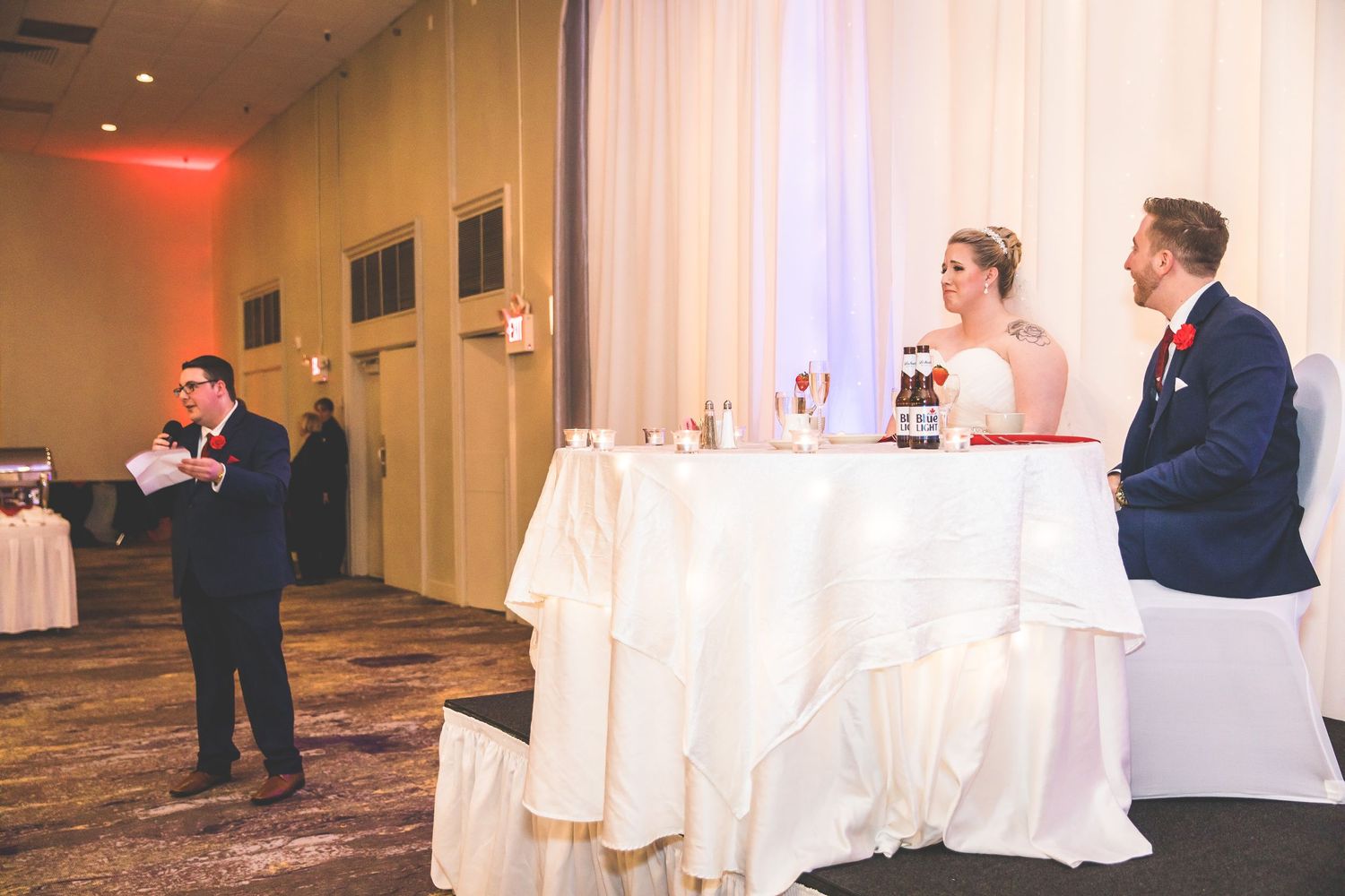 Wedding reception toast being given while couple sits at head table.