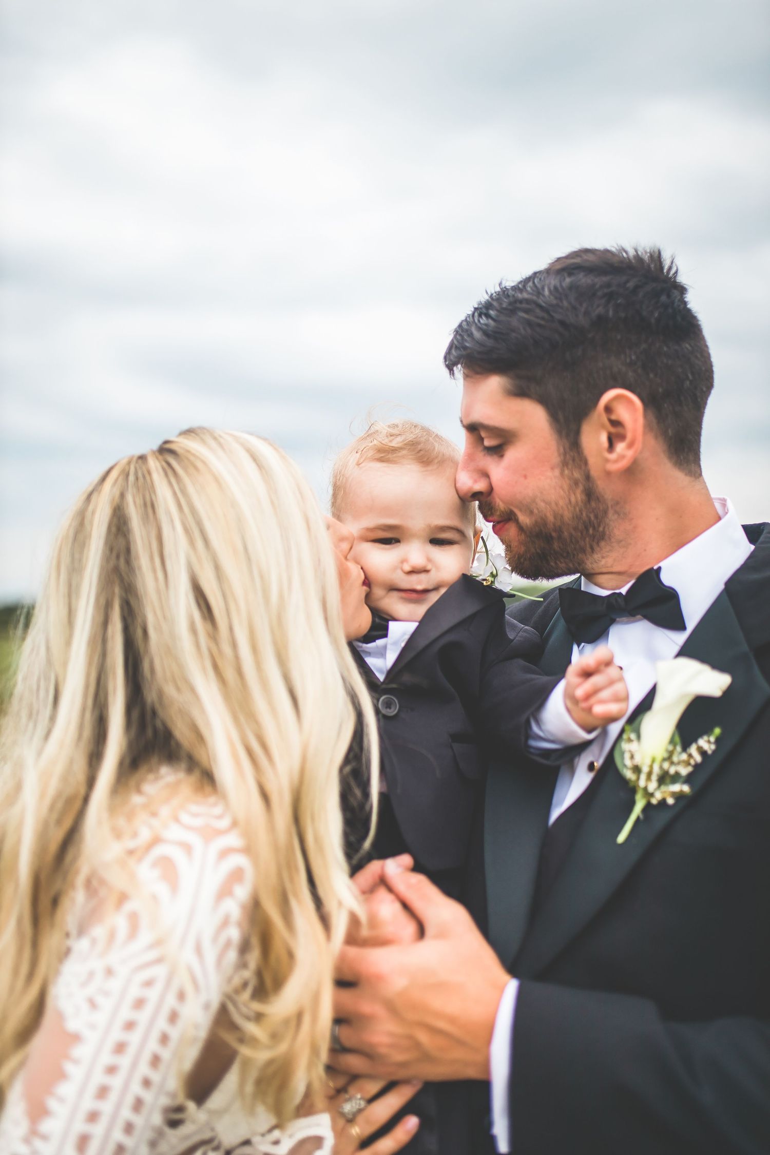 A tender family moment shared between three people during an outdoor wedding celebration.