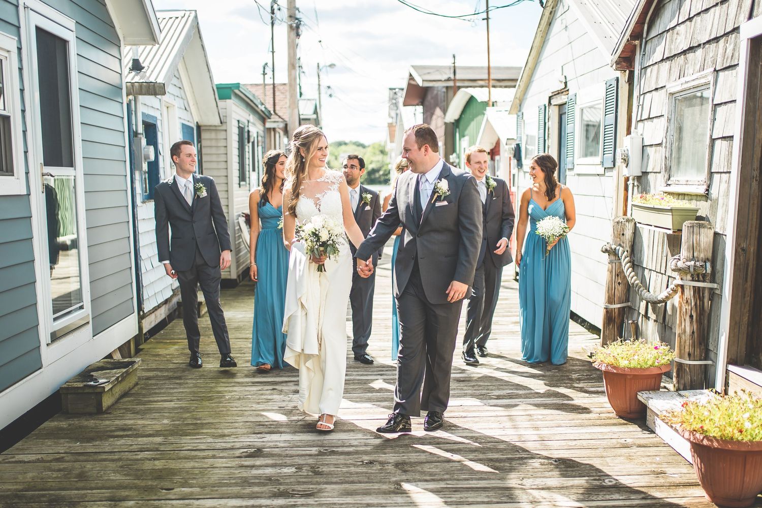 Wedding party poses along a charming white clapboard building with blue trim.