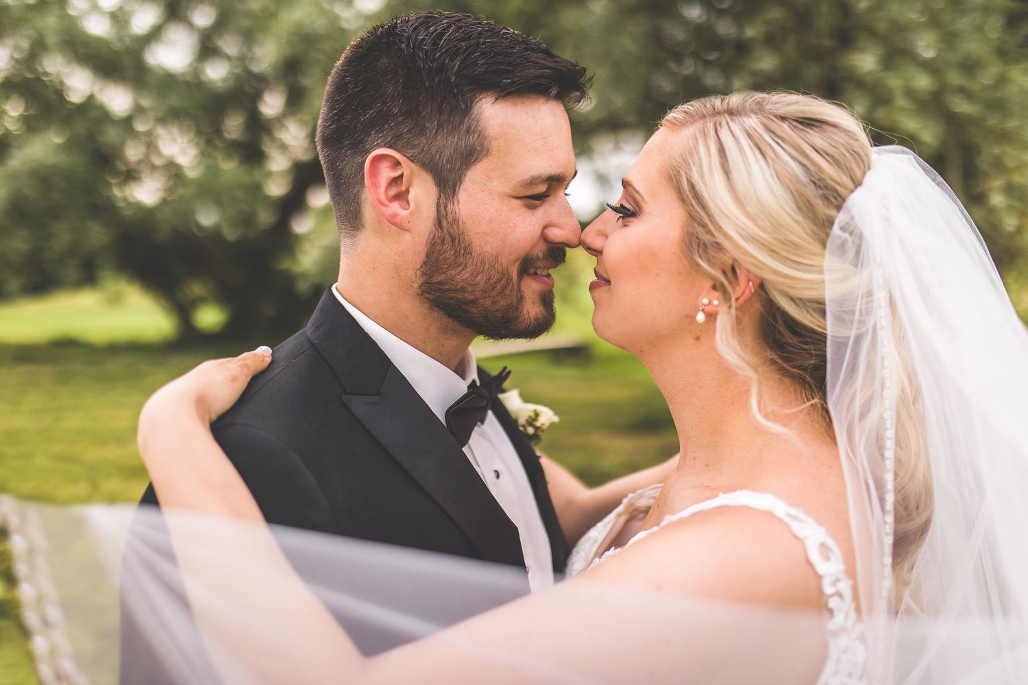Close-up romantic moment between bride and groom outdoors with soft natural lighting.