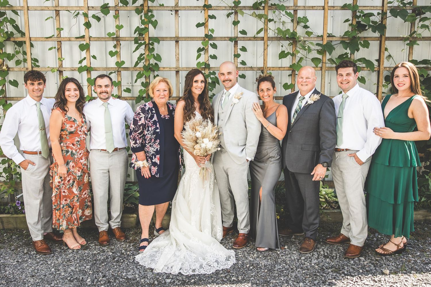 Wedding party and guests gathered outdoors for a formal group photo in elegant attire.
