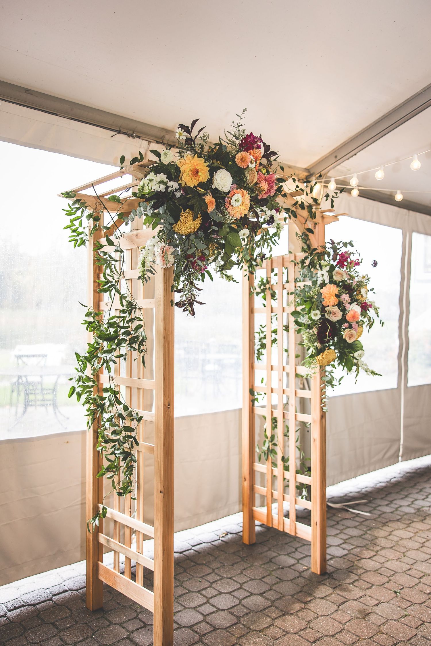 Wedding venue with wooden posts decorated with lush floral arrangements and greenery.