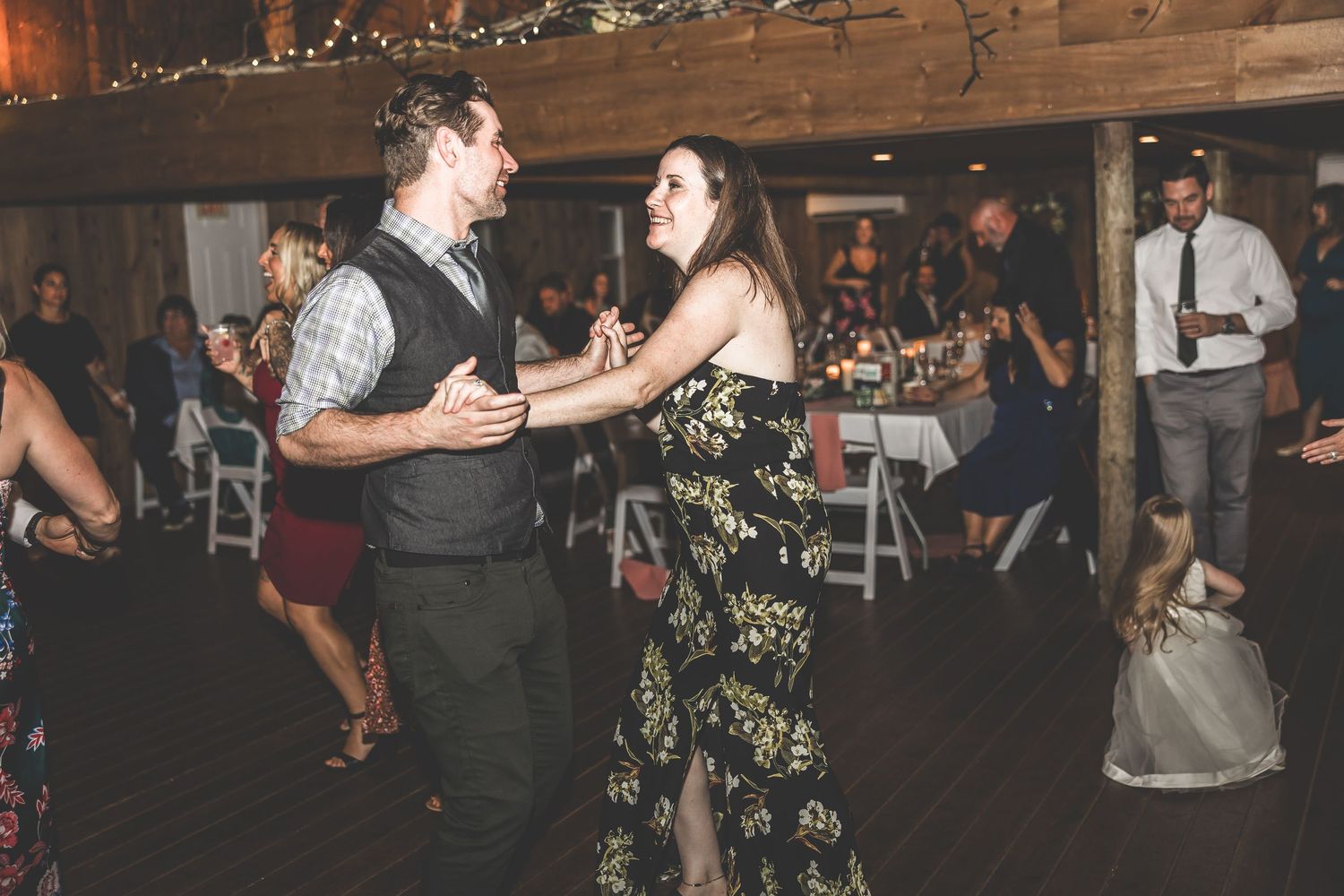 Wedding reception dance floor filled with guests enjoying themselves under warm lighting.