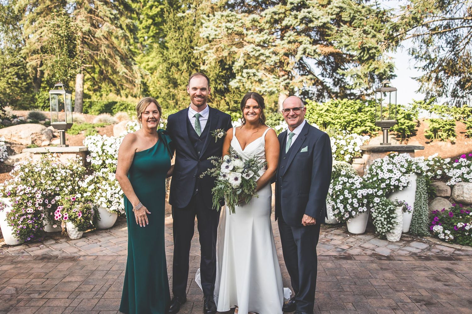 Wedding party posing for formal photos in an outdoor garden setting.
