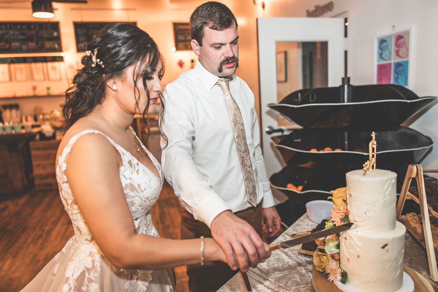 Wedding couple cuts into their white wedding cake during reception.