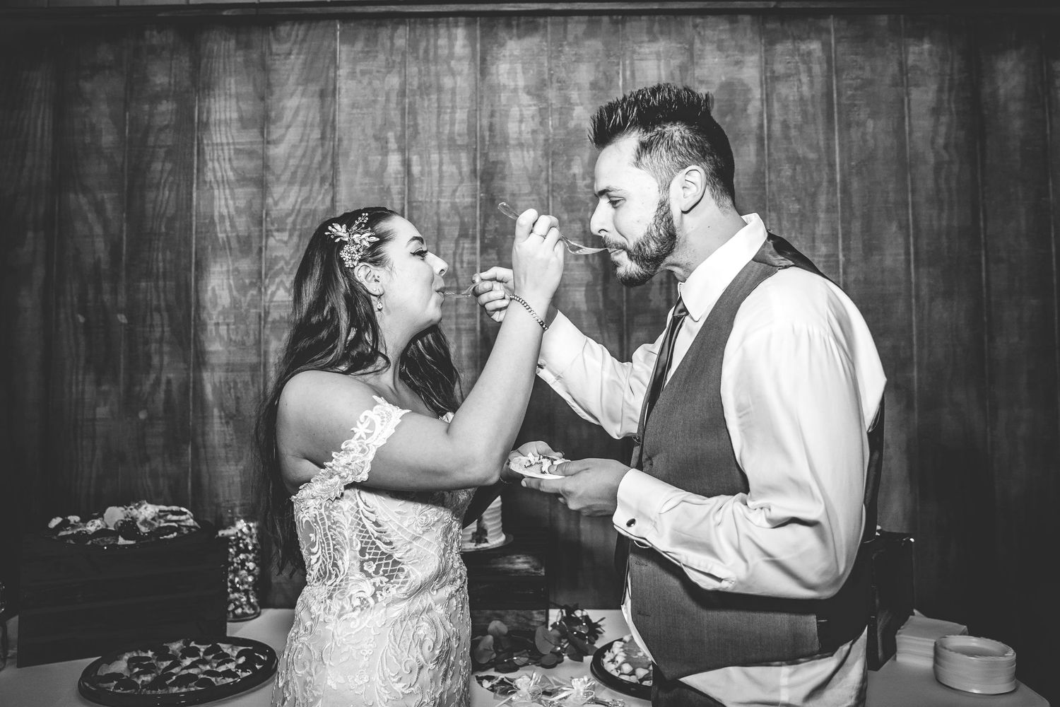 Black and white photos of couple feeding each other wedding cake at reception.
