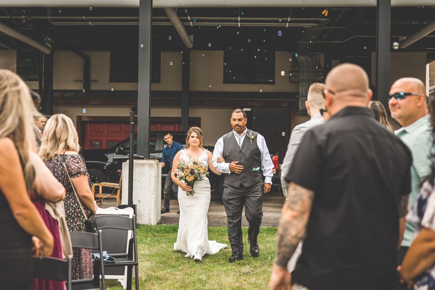 Wedding ceremony in progress at rustic outdoor venue with covered pavilion.