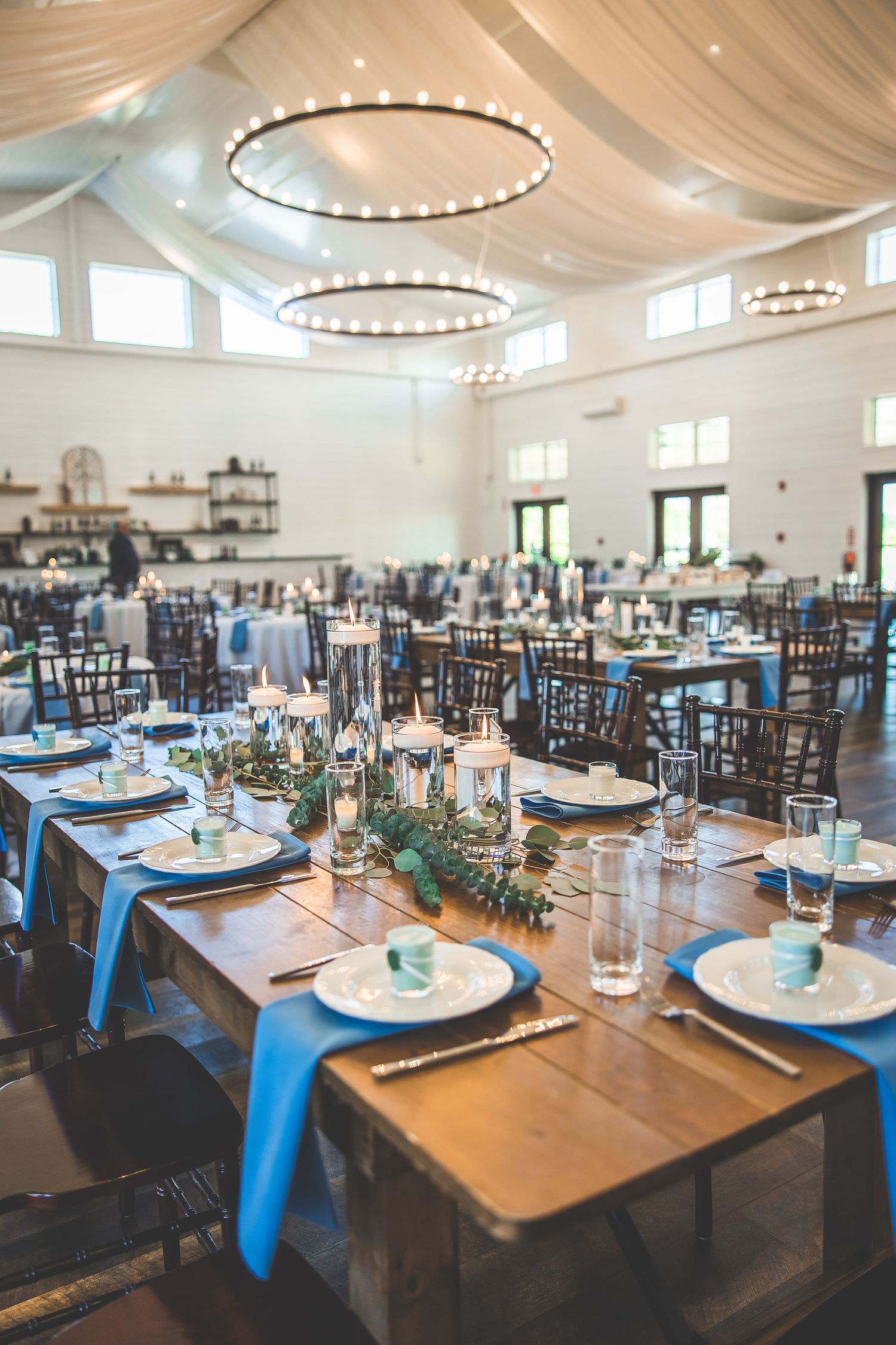 Elegant wedding reception venue with draped fabric ceiling, chandeliers and tables set for dinner.