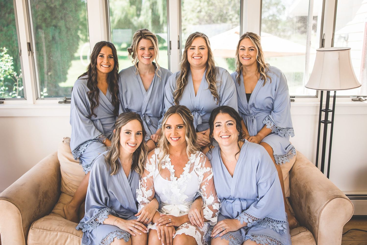 Wedding party relaxing together on couch in matching blue outfits.