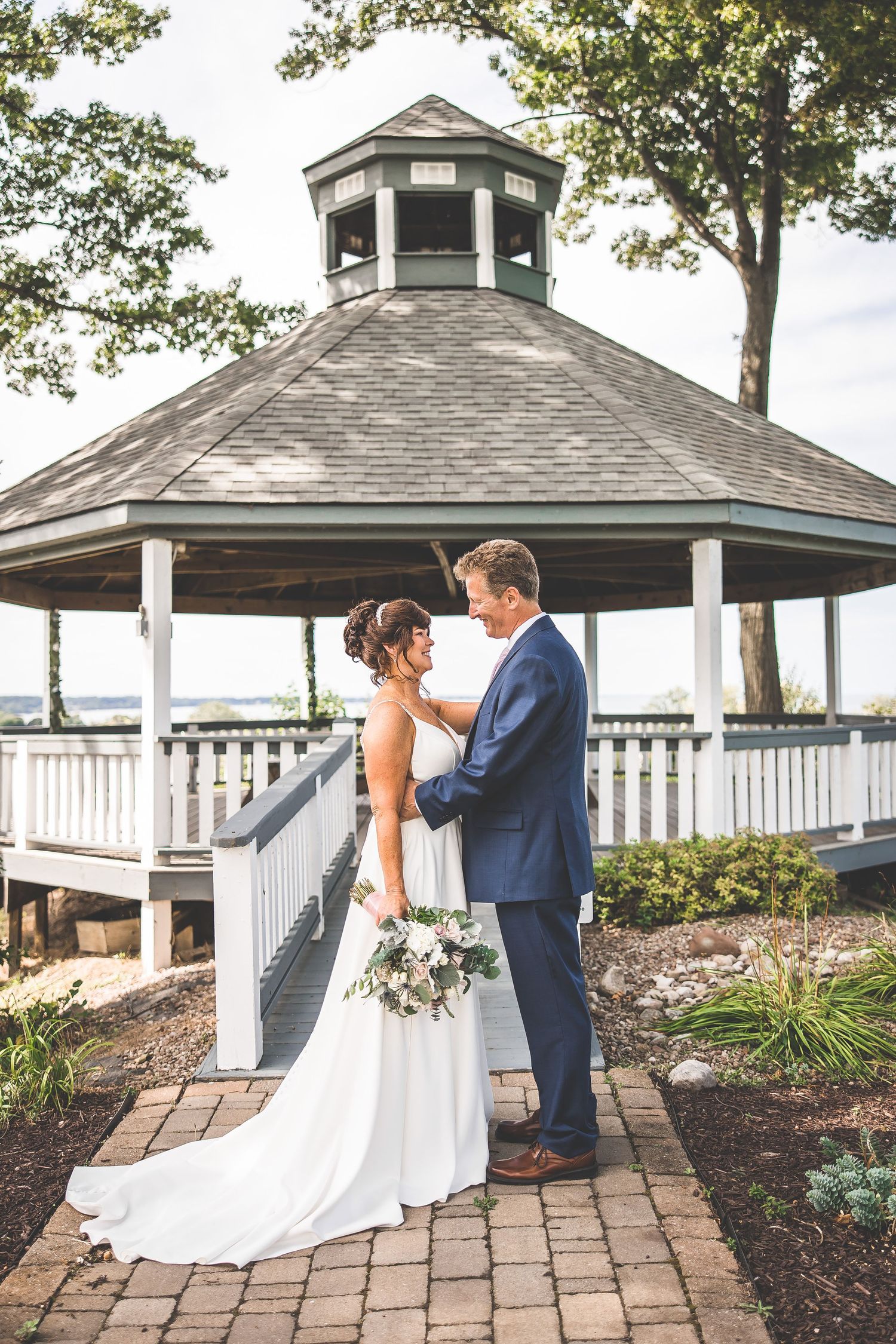 Wedding photos taken at a white gazebo with brick pathways and landscaped gardens.