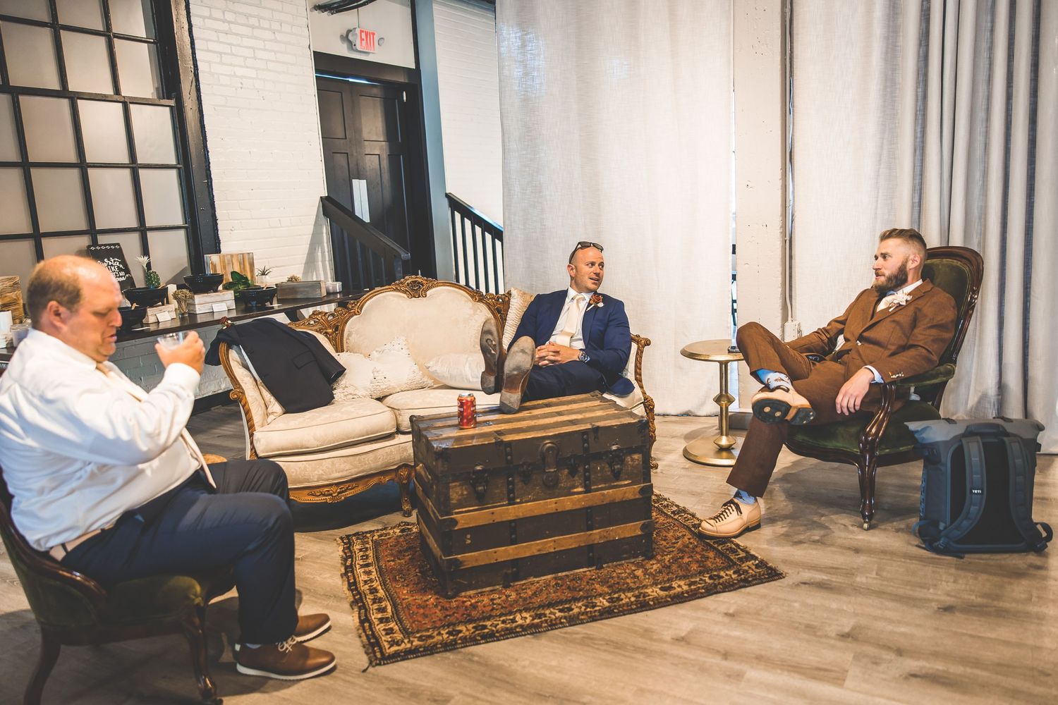 Wedding guests relaxing on vintage furniture in an elegant lounge area.