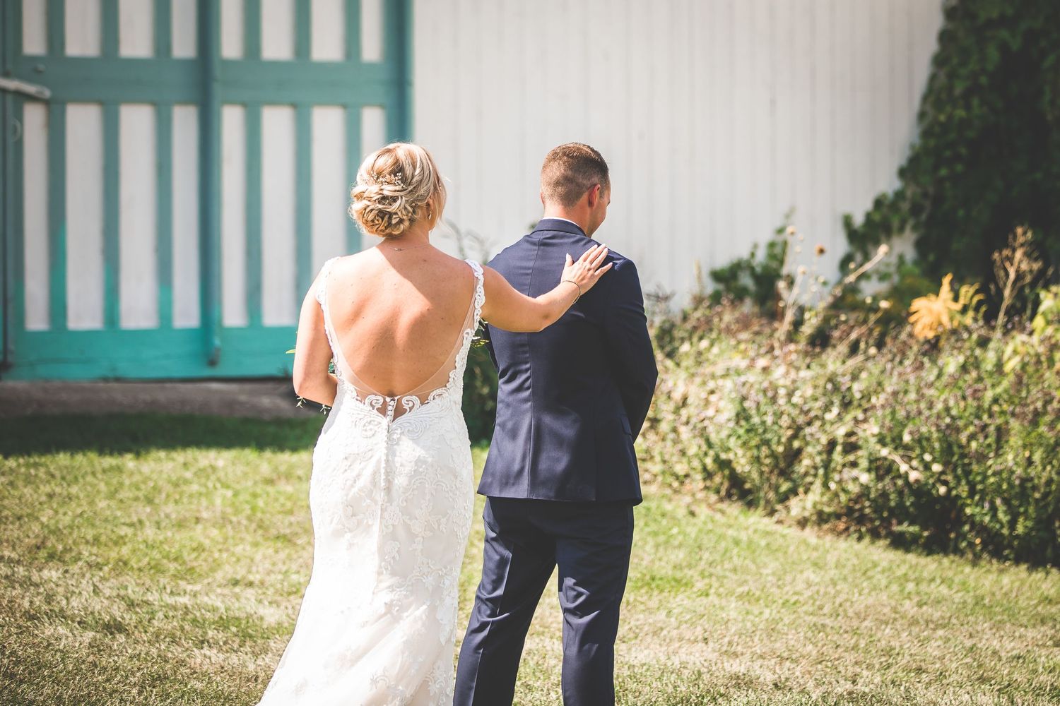 A couple in wedding attire shares an intimate moment in a garden with turquoise accents.