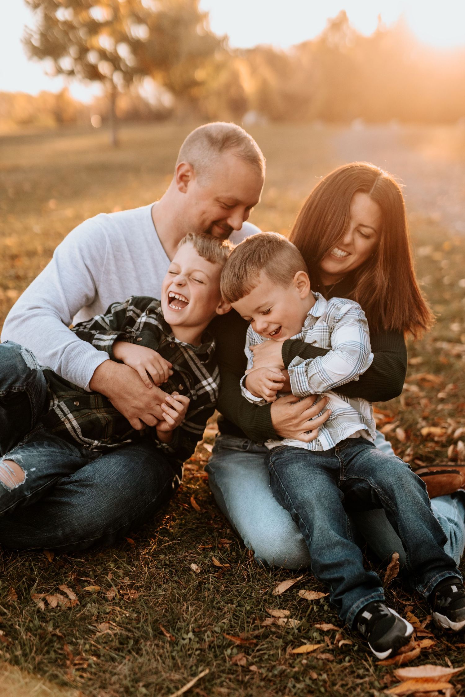 Candid family photo session at sunset showing playful moments on fallen leaves.